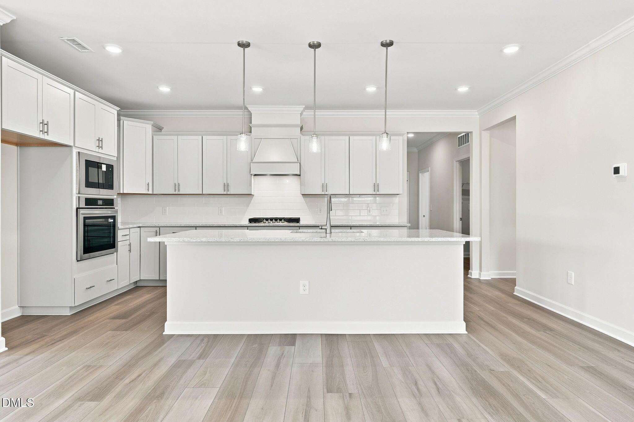 Modern kitchen with white cabinets, island, and stainless steel appliances in The Magnolia B at Retreat at North Main.
