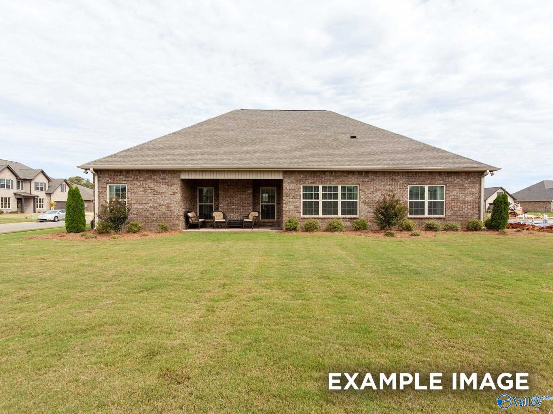 Single-story brick home rear with covered patio, outdoor seating, and lush green lawn in Briercreek, Meridianville, Alabama - Davidson Homes The Finleigh