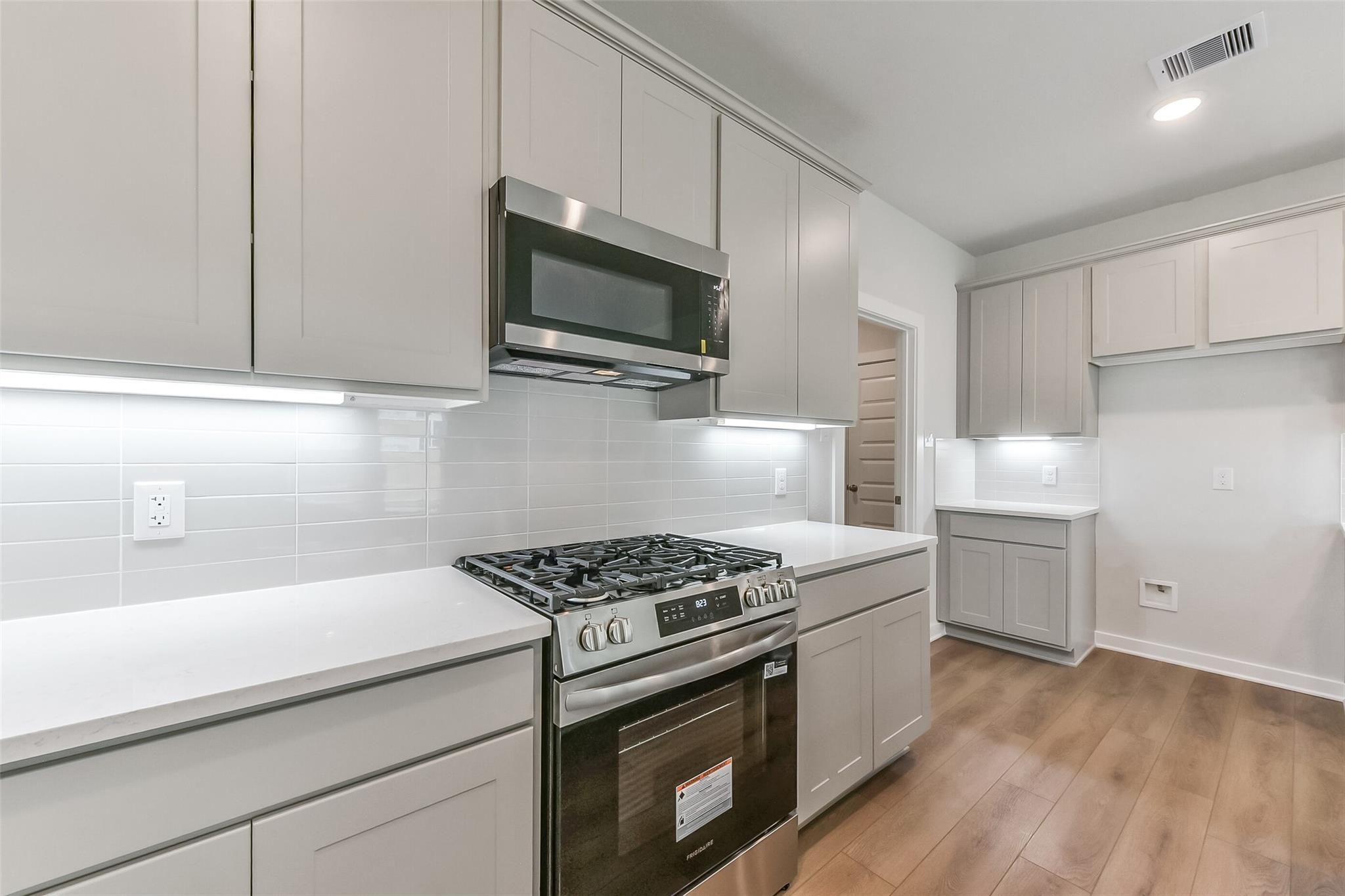 Modern kitchen featuring white shaker cabinets, quartz countertops, subway tile backsplash, stainless steel appliances in Davidson Homes The Tierra C, Dayton Texas