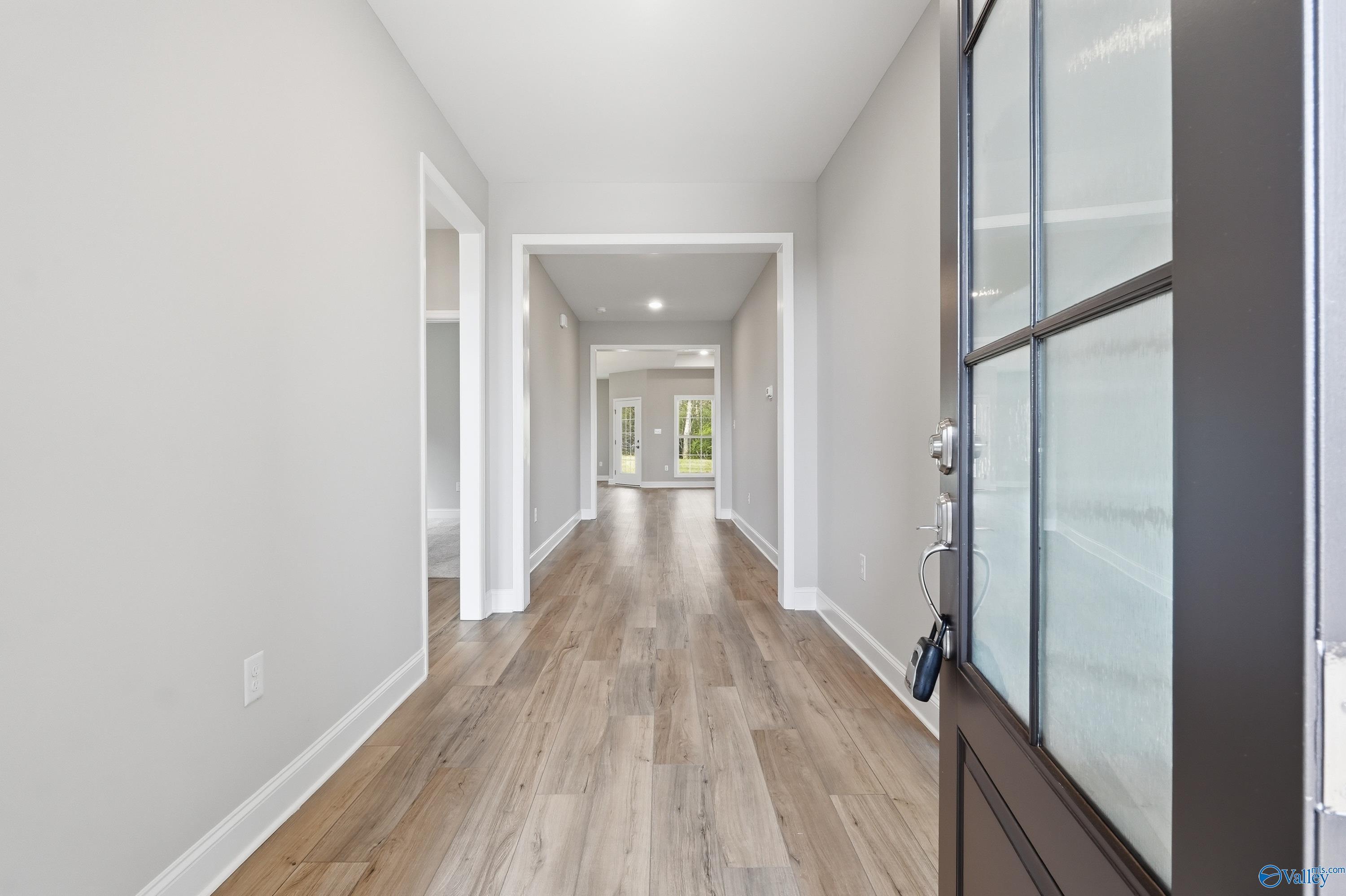 Spacious entry hallway with hardwood floors, arched openings, and glass front door in Davidson Homes The Harrison B, Decatur, AL
