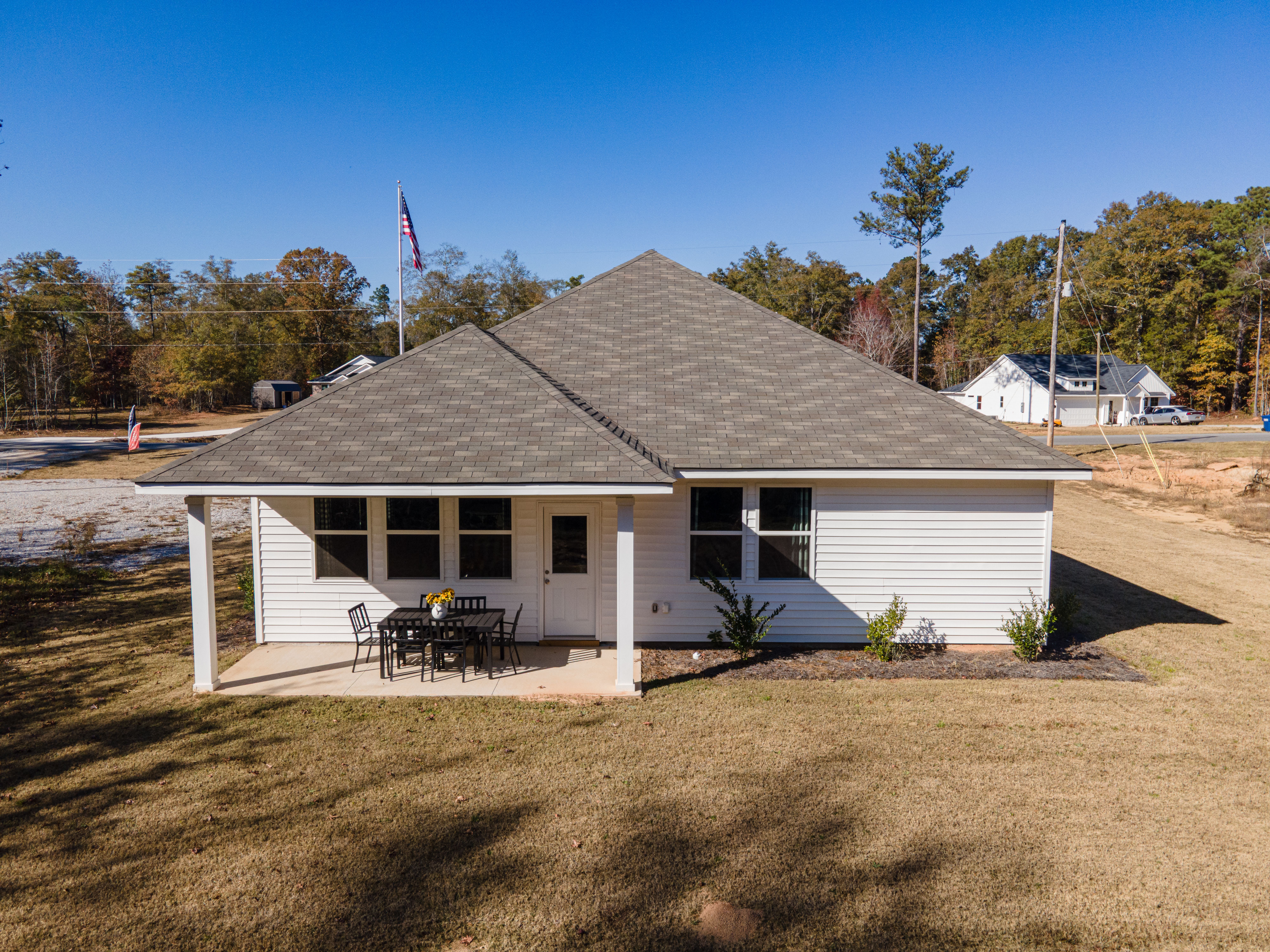 Spacious covered patio at Silver Oak in Cusseta Alabama with black metal dining table chairs and sunflower vase by Evermore Homes