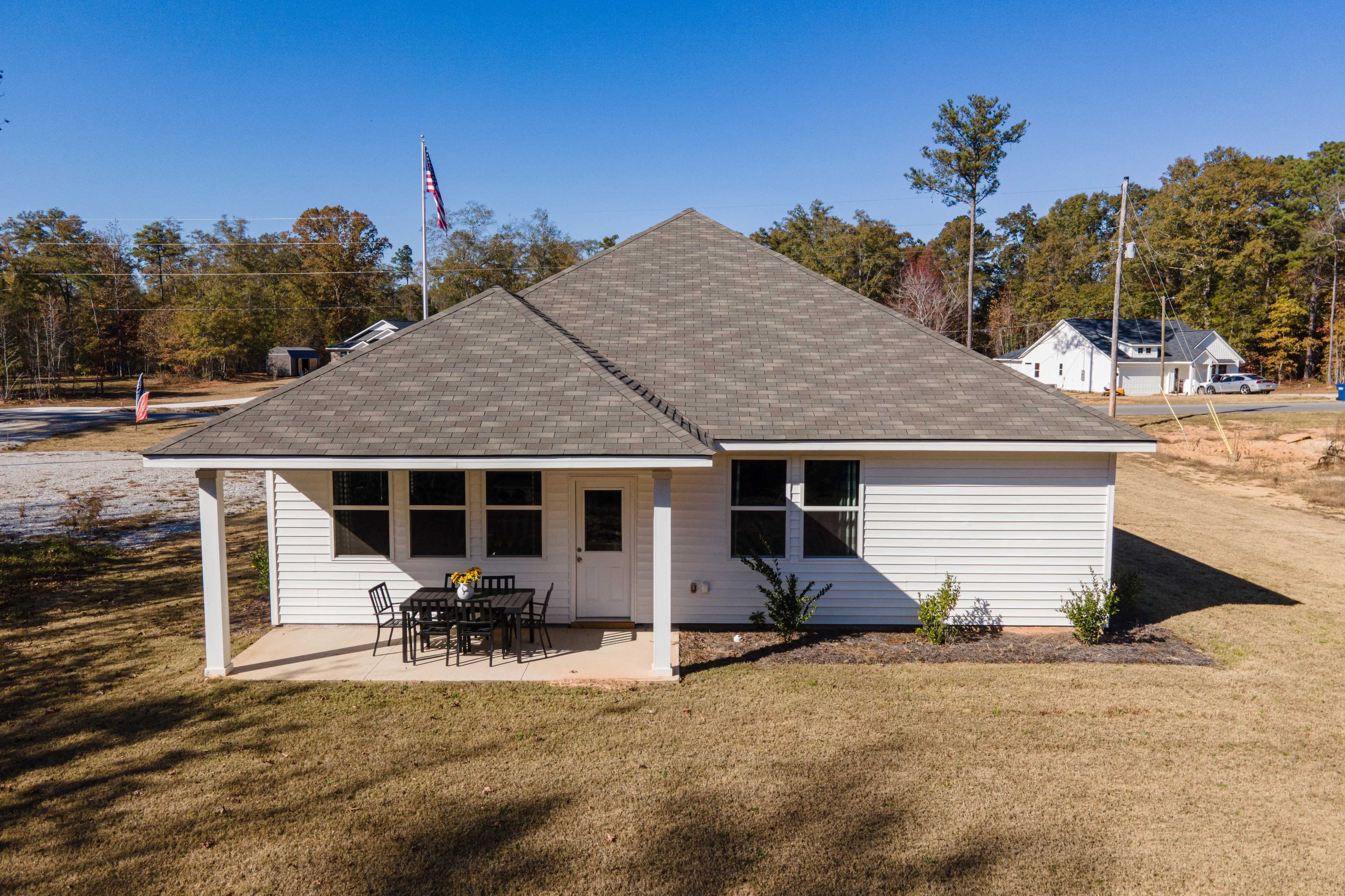 Spacious covered patio at Silver Oak in Cusseta Alabama with black metal dining table chairs and sunflower vase by Evermore Homes
