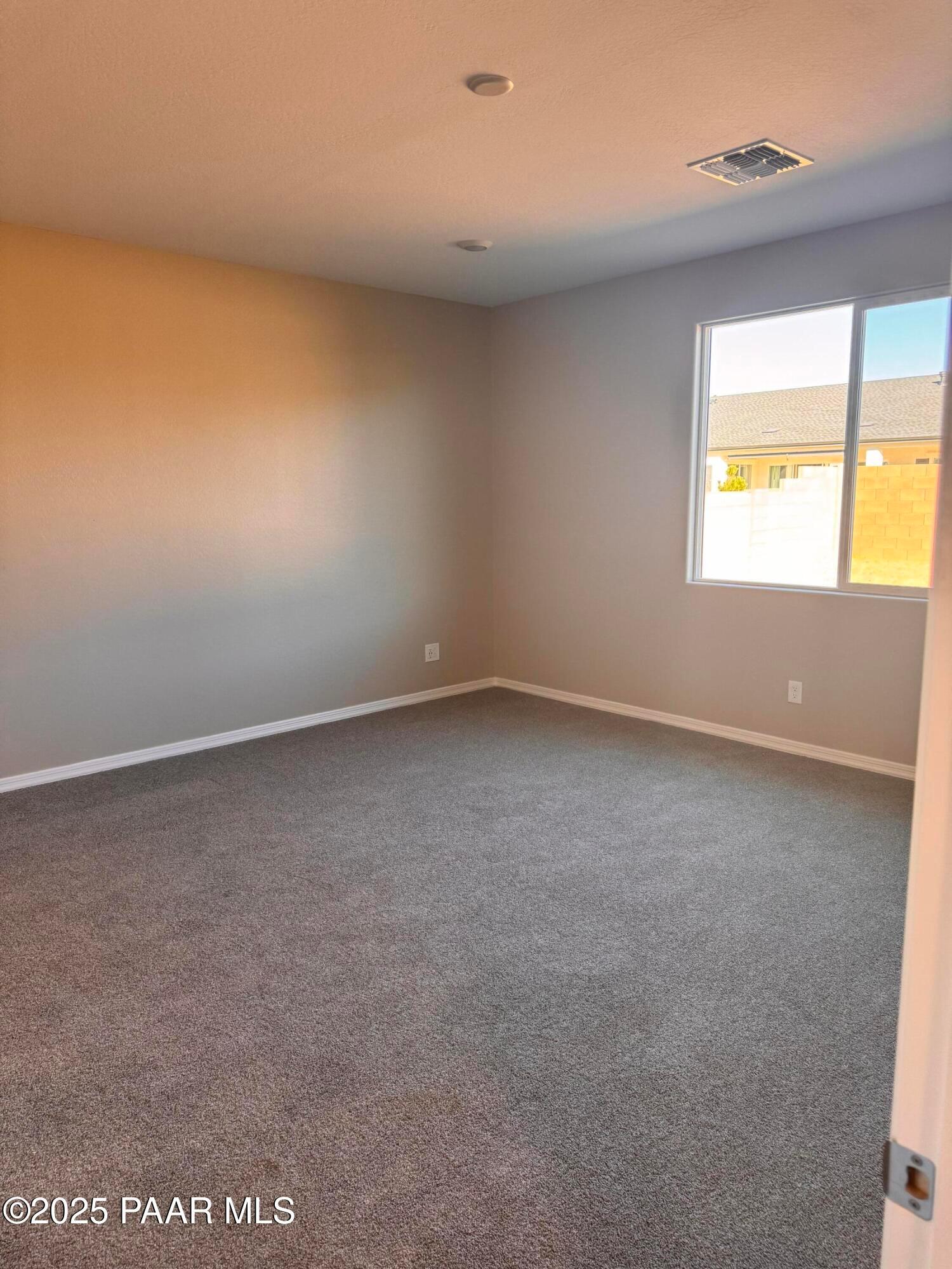 Empty bedroom featuring gray carpet, neutral walls, large window with neighborhood view in Davidson Homes The Sunrise II A, Prescott, Arizona