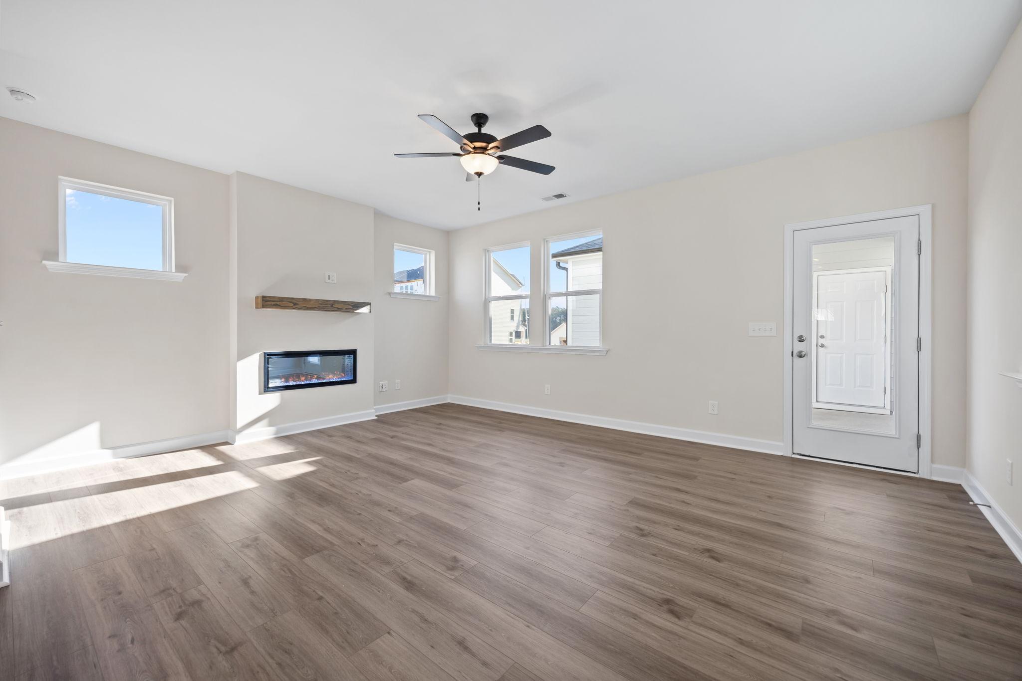 Spacious living room at Forestville Yard in Knightdale, NC, featuring modern fireplace, ceiling fan, and wood-style flooring.