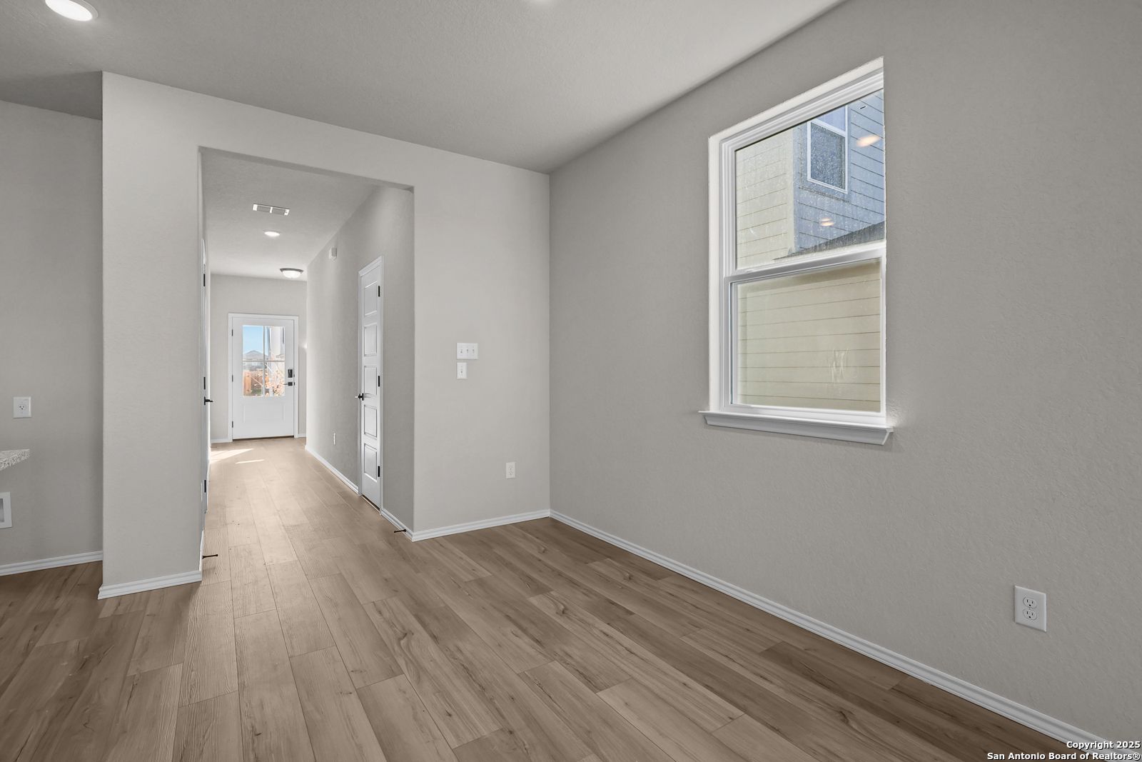 Spacious hallway with light oak floors, gray walls, and recessed lighting in The Brazos C 5-bedroom home, San Antonio