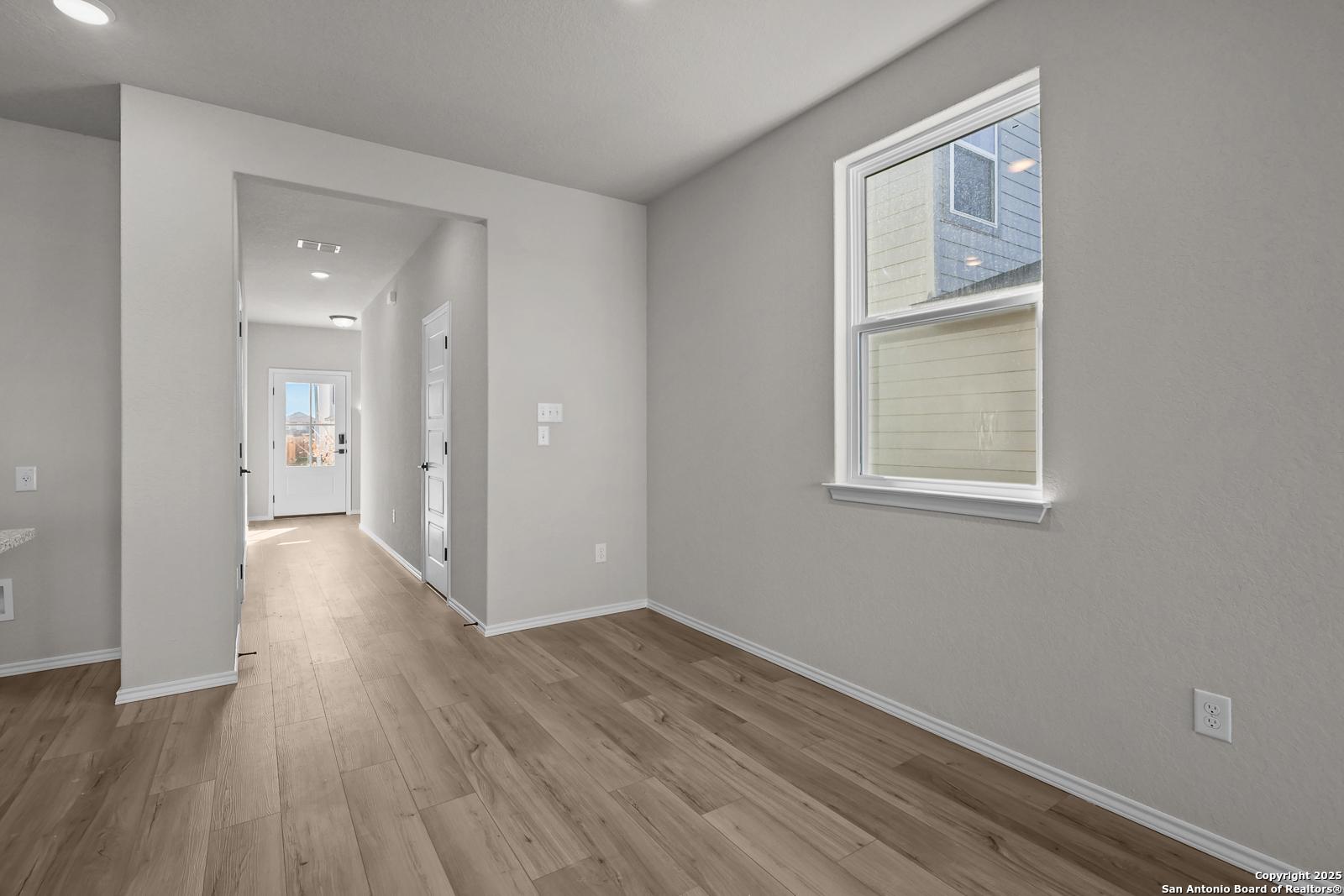 Spacious hallway with light oak floors, gray walls, and recessed lighting in The Brazos C 5-bedroom home, San Antonio