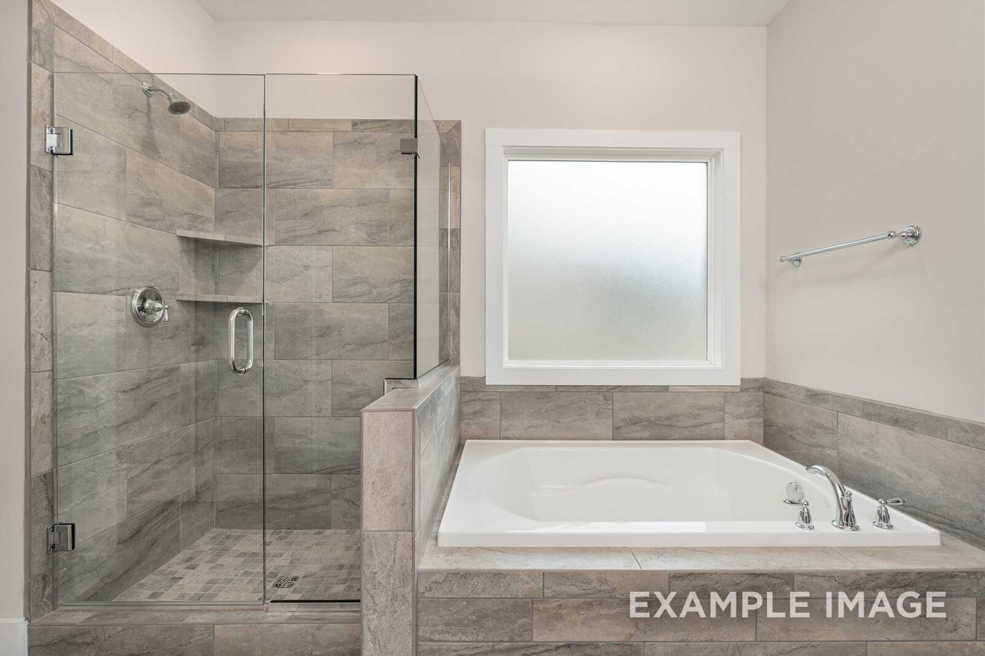 Spacious master bathroom in The Rockford by Davidson Homes featuring tiled walk-in shower and freestanding soaking tub
