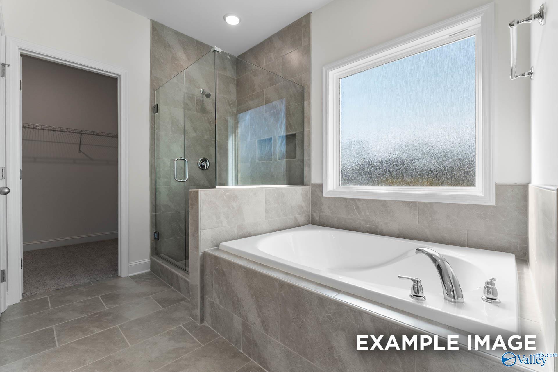 Elegant master bathroom with frameless glass shower, soaking tub, and walk-in closet in Davidson Homes The Harrison C, Athens AL