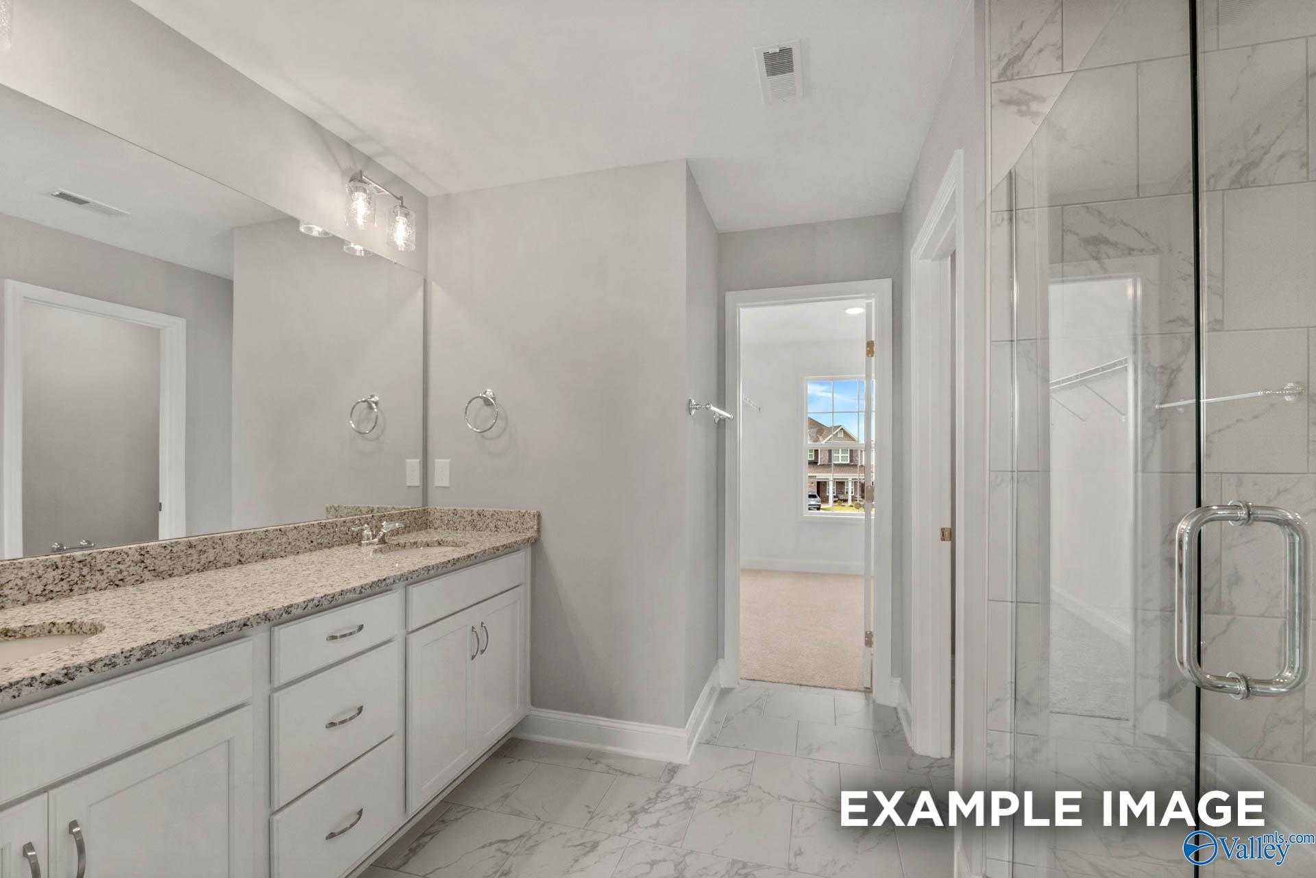 Elegant master bathroom with double granite vanity, frameless glass shower, and marble tiles in Davidson Homes Shelby B, Athens AL