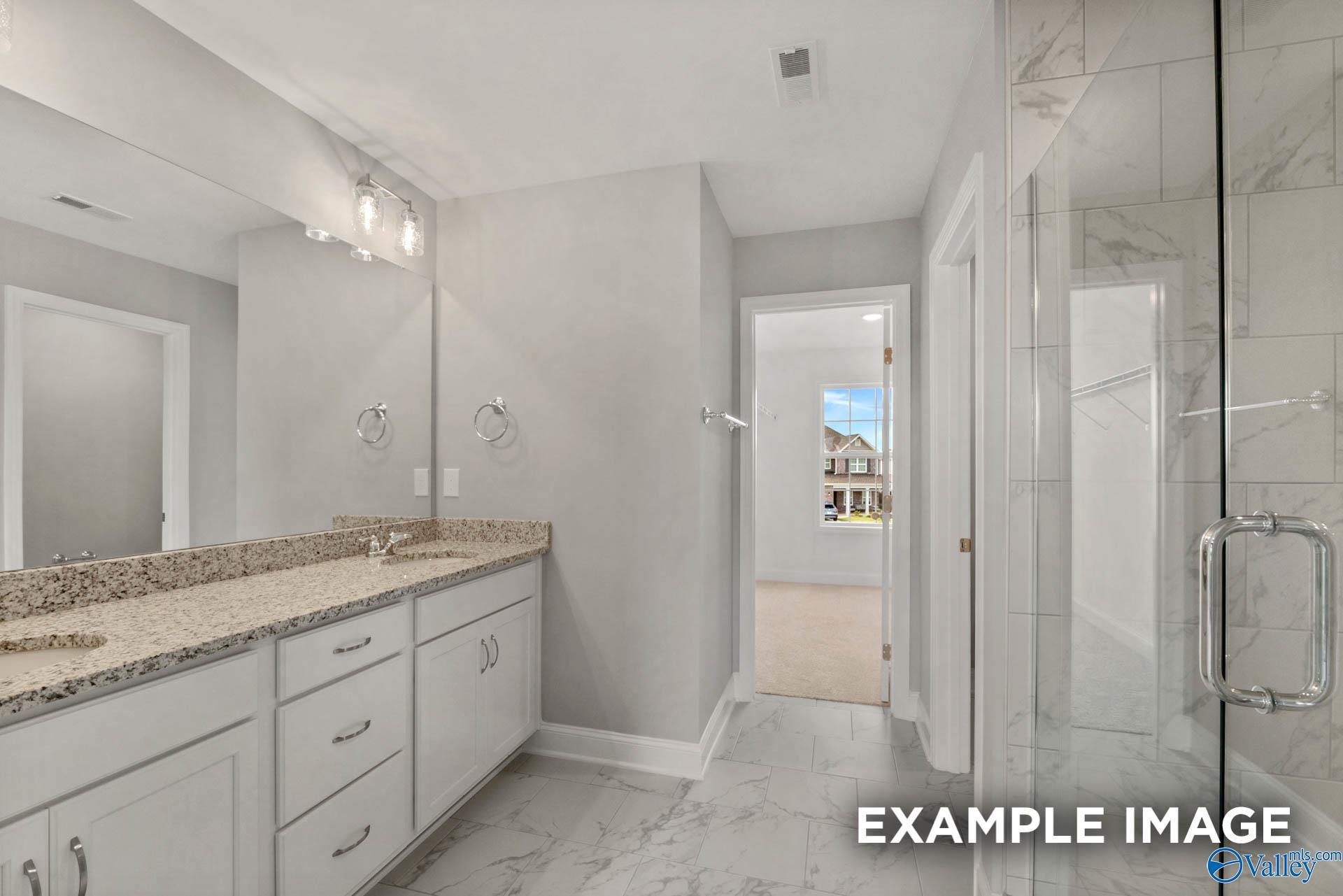 Elegant master bathroom with double granite vanity, frameless glass shower, and marble tiles in Davidson Homes The Shelby B, New Market, Alabama