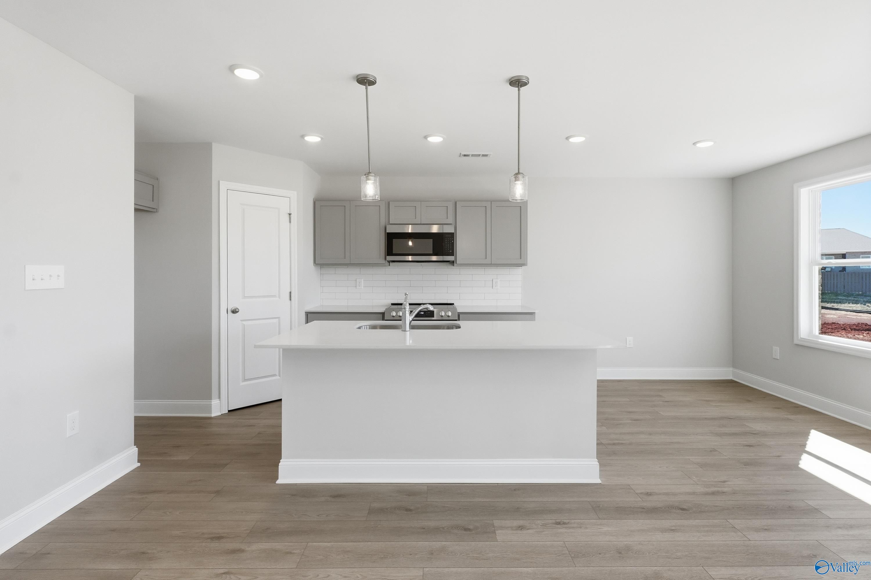 Modern white kitchen with shaker cabinets, stainless steel appliances, and oversized island in Davidson Homes The Butler, New Market, AL