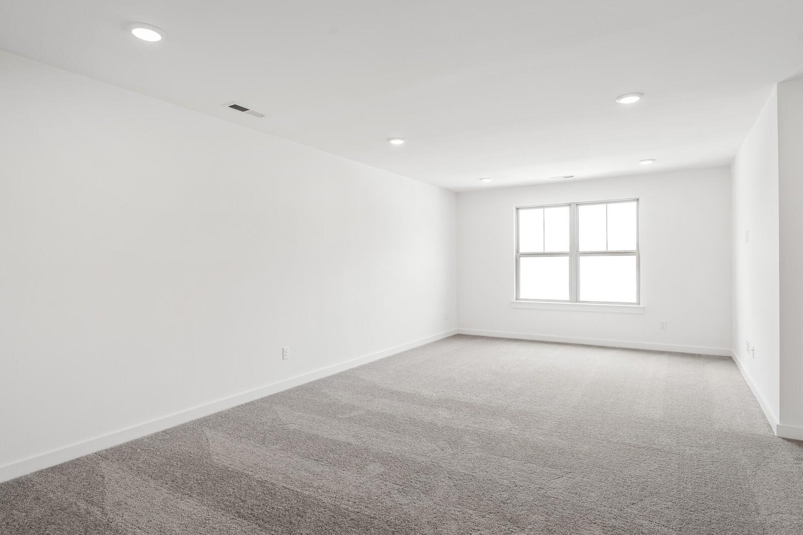 Bright, spacious bedroom with recessed lighting and neutral carpeting in The Ridgeport C plan at Woods Crossing, Gallatin.