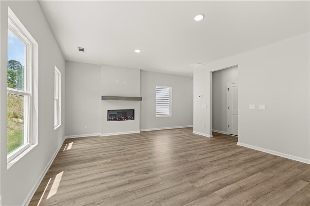 Bright living room with modern fireplace and wood-style flooring in The Hartwell A floor plan at The Bluffs, Canton, GA.
