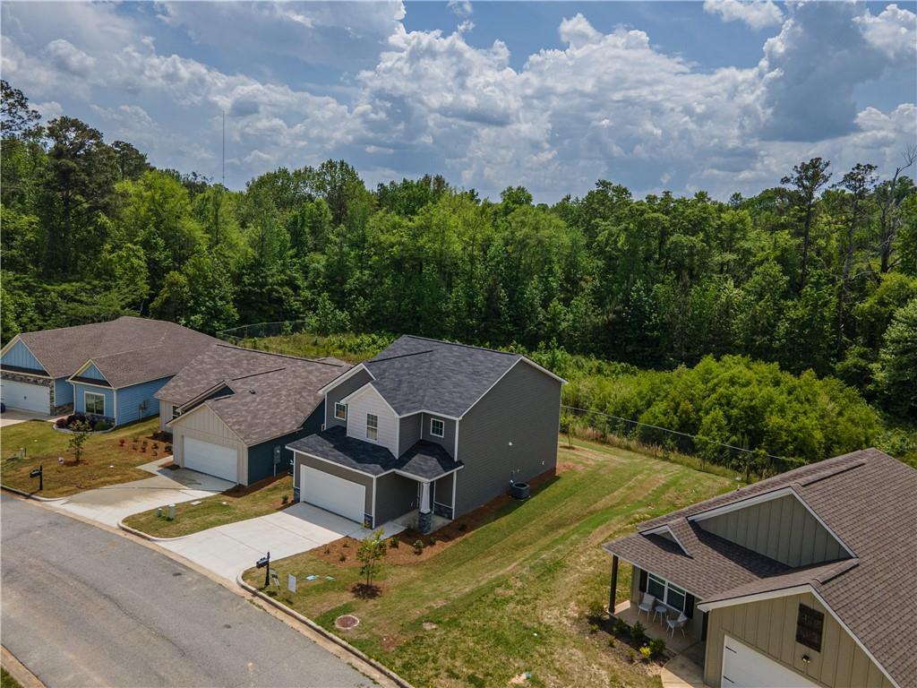 Aerial view of two-story gray The Bartlett home with 2-car garage amid wooded lots in Summer Vineyard, Phenix City, Alabama