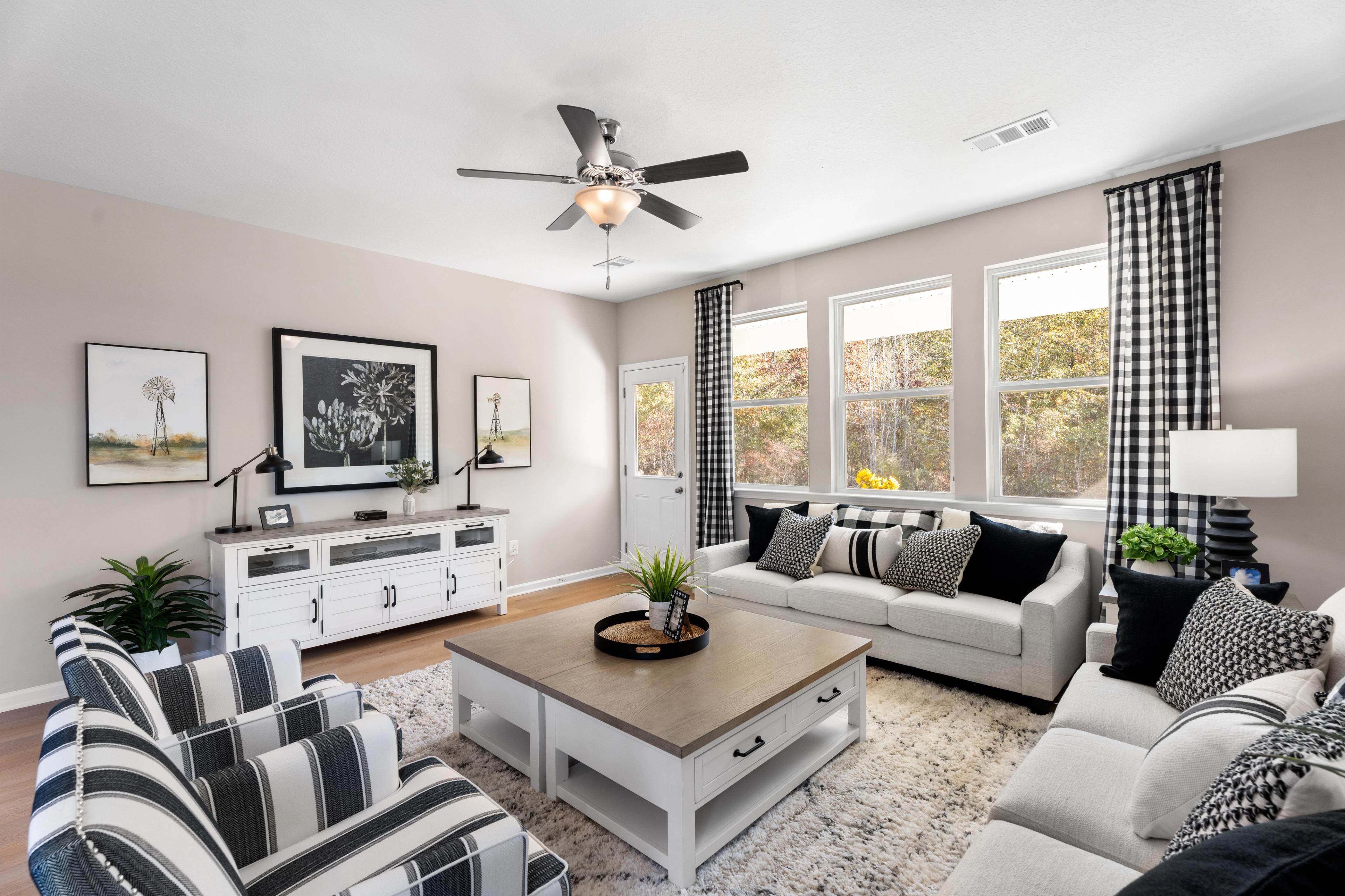 Open-concept living room and kitchen in Silver Oak Cusseta AL by Evermore Homes with white sofa, hardwood floors, ceiling fan