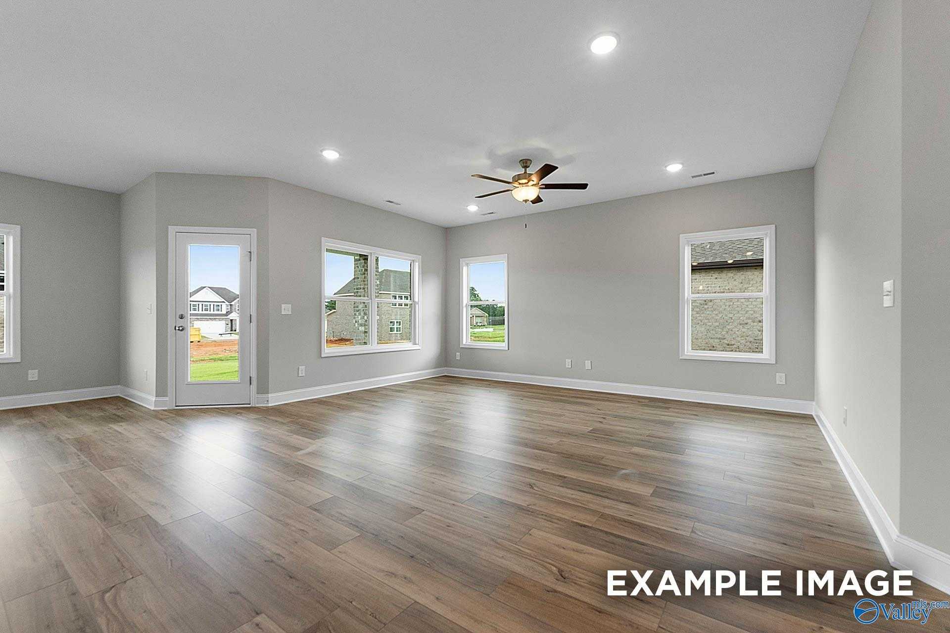 Spacious empty living room with luxury vinyl plank floors, large windows, and ceiling fan in Davidson Homes The Franklin E, Hazel Green, Alabama