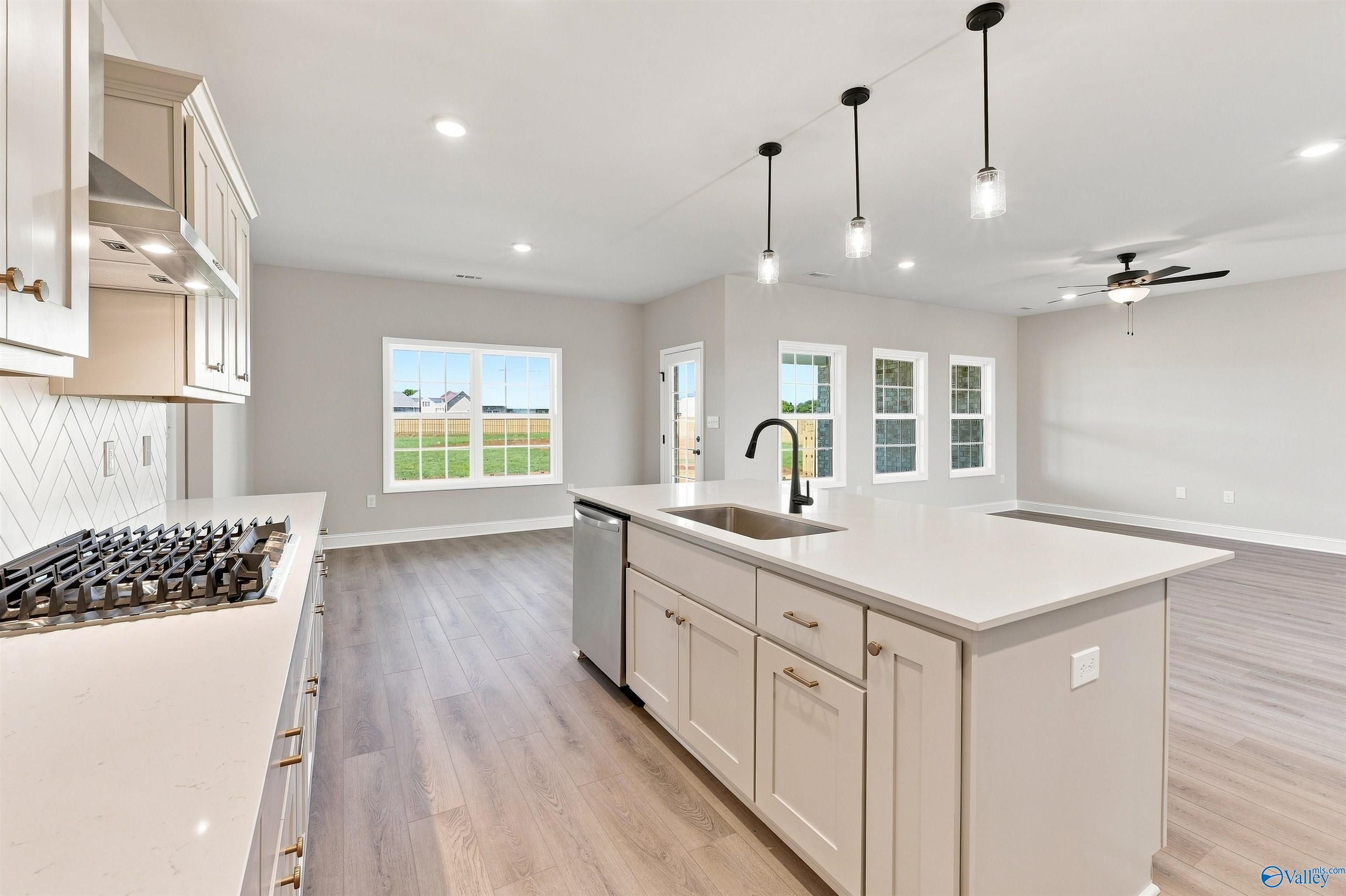 Modern kitchen island with quartz countertops and pendant lighting in The Oxford floor plan at Kendall Farms, Toney, AL.