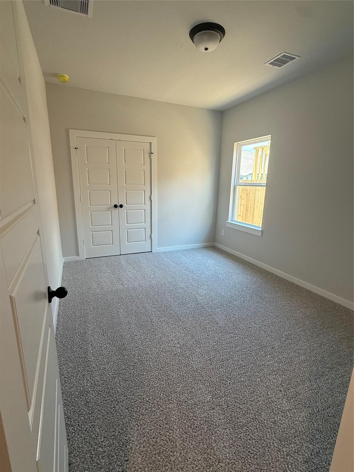 Bright secondary bedroom with carpet and double-door closet in The Sorrento E floor plan at Sundance Cove, Crosby, Texas.
