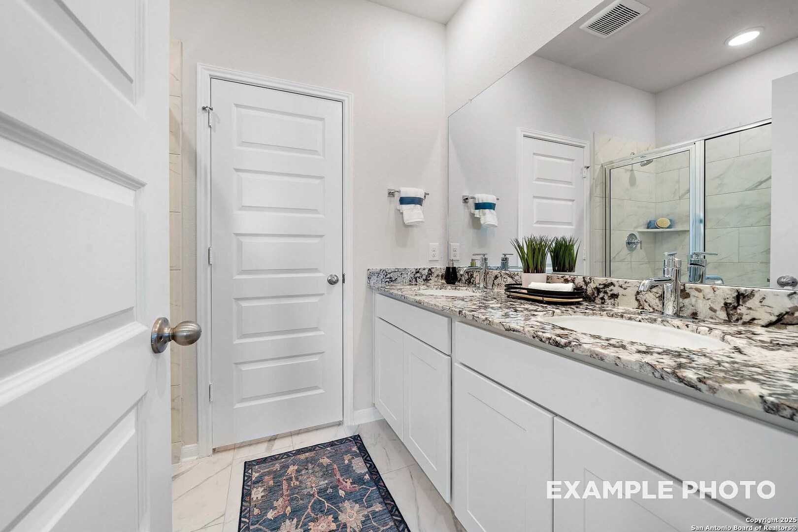 Elegant double vanity bathroom with quartz counters, large mirror, and glass shower in Davidson Homes The San Marcos D, Agave, San Antonio