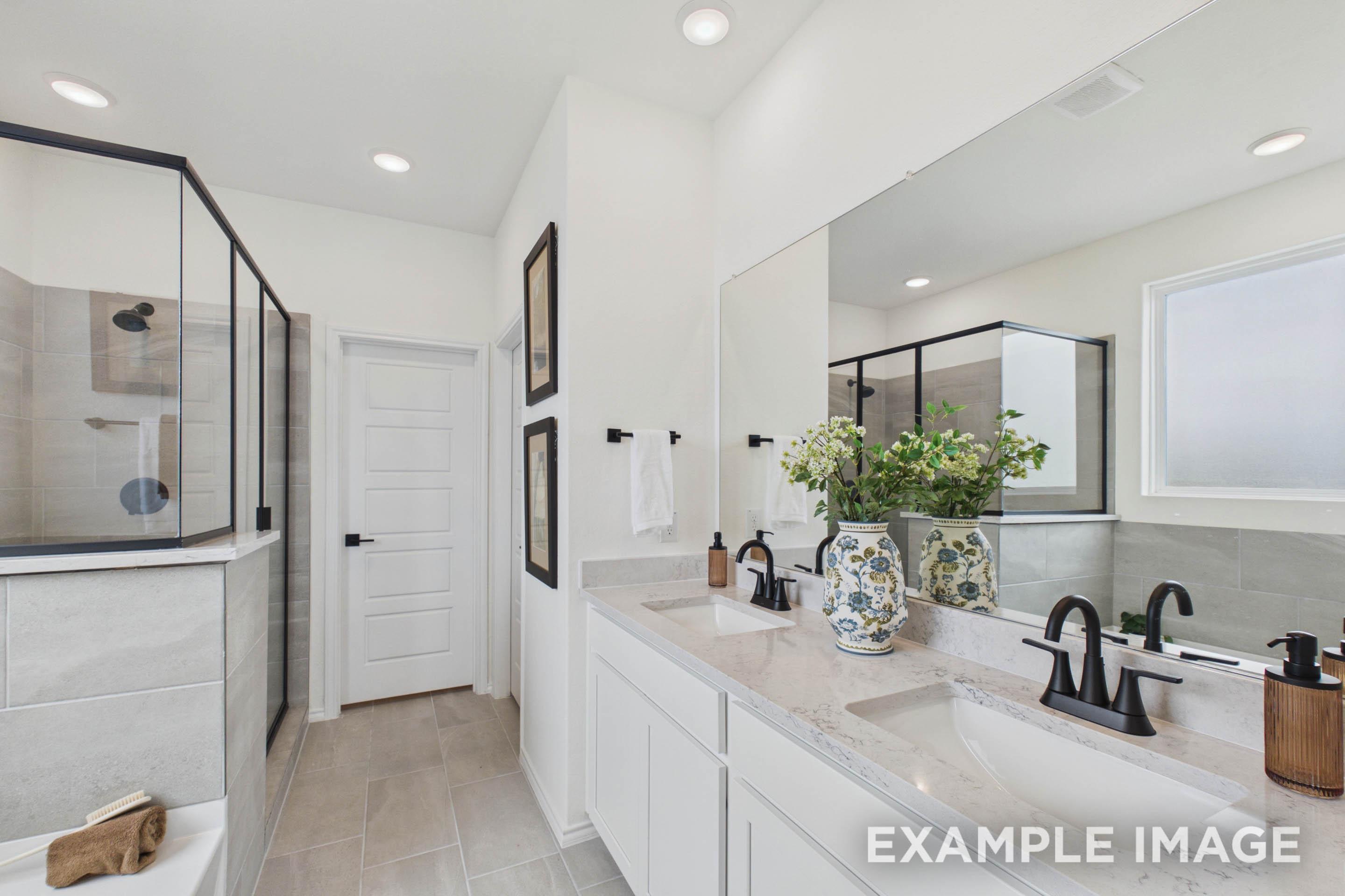 Master bath in The Laurel G featuring a dual vanity with quartz countertops, sleek black fixtures, and a walk-in shower.