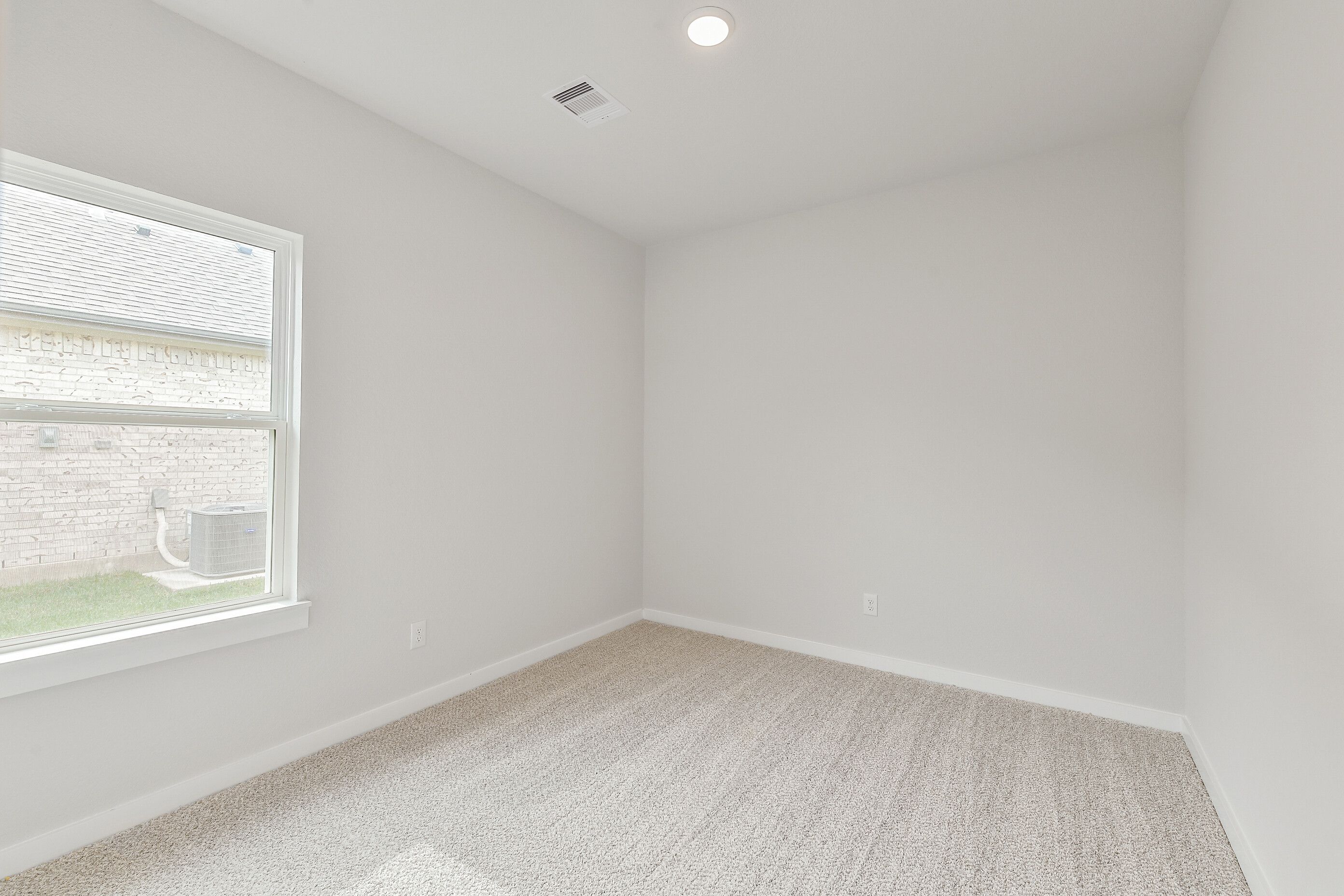 Empty secondary bedroom featuring beige carpet, light walls, and large window in Davidson Homes The Colorado G, Magnolia, Texas