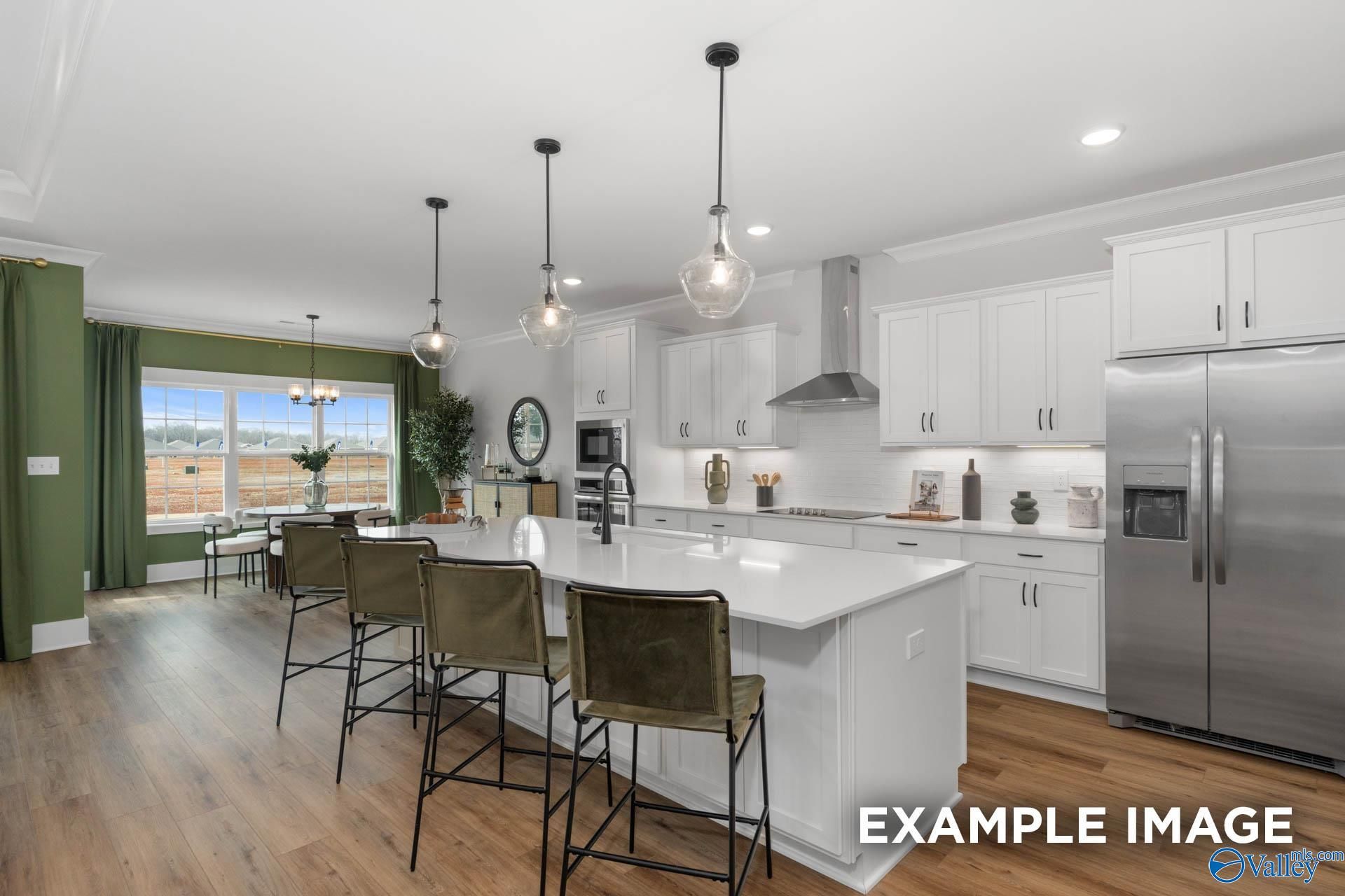Modern white kitchen island with bar stools, stainless fridge, and green window wall in Davidson Homes The Finleigh, Decatur AL