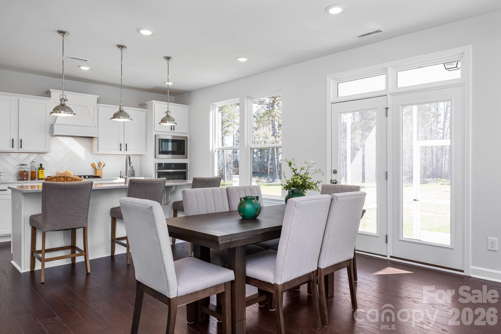 Open-concept kitchen and dining area with white cabinetry, pendant lights, and French doors in Davidson Homes Hemlock D, Belmont NC
