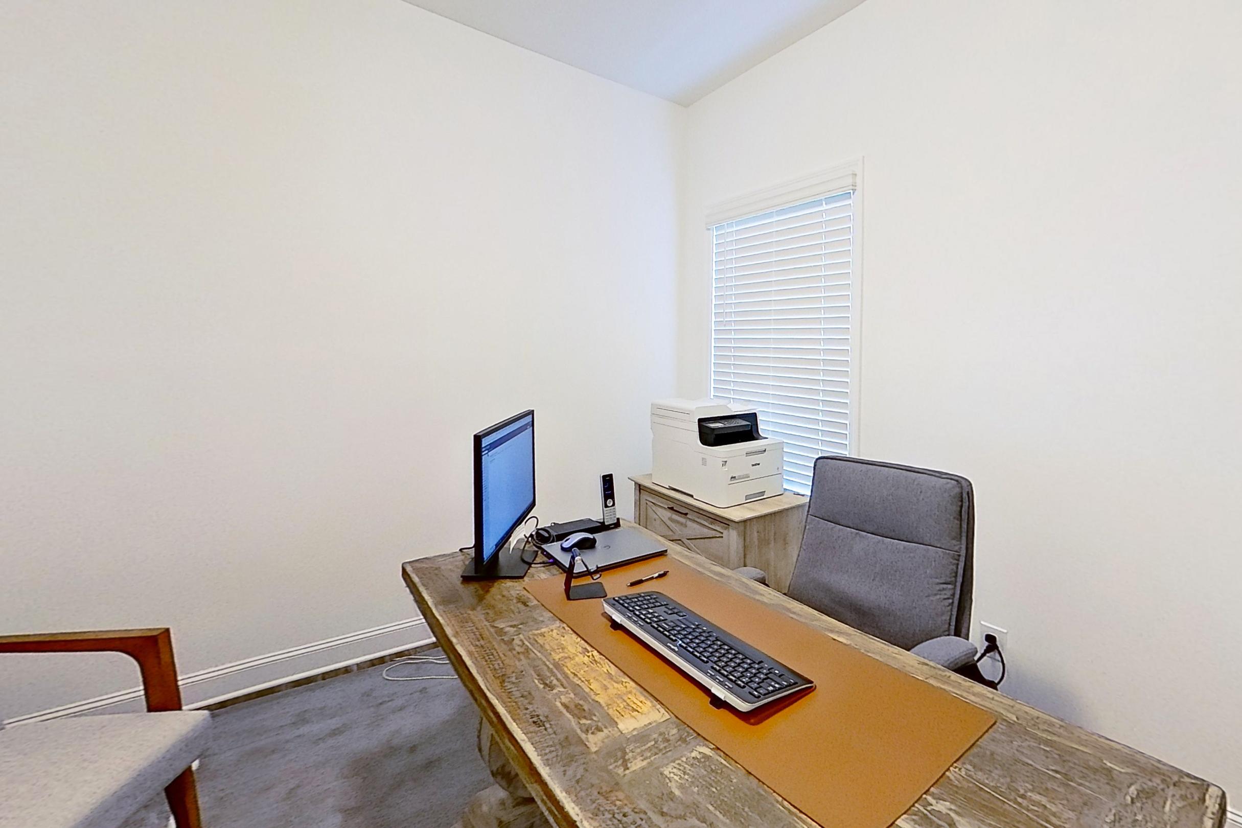 Spacious home office in The Cumberland B with rustic wooden desk, computer monitor, printer, and gray ergonomic chair, Decatur AL design