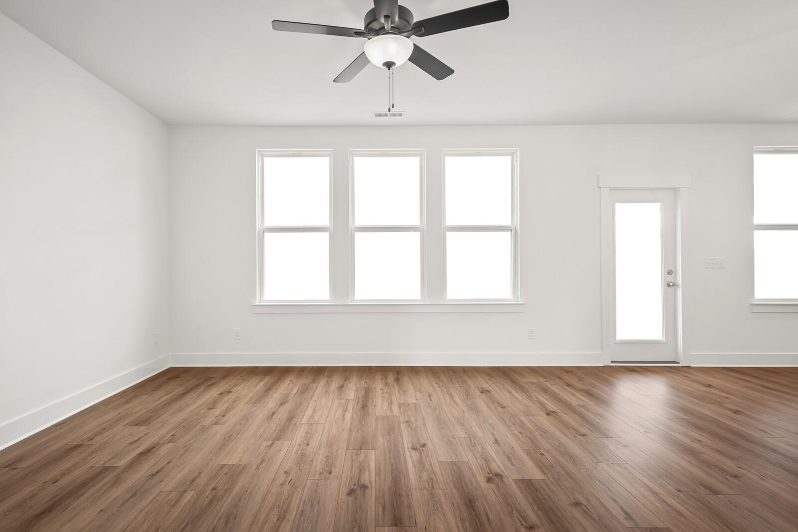 Bright living room with hardwood floors, large windows, and ceiling fan in The Logan C, Gallatin, Tennessee