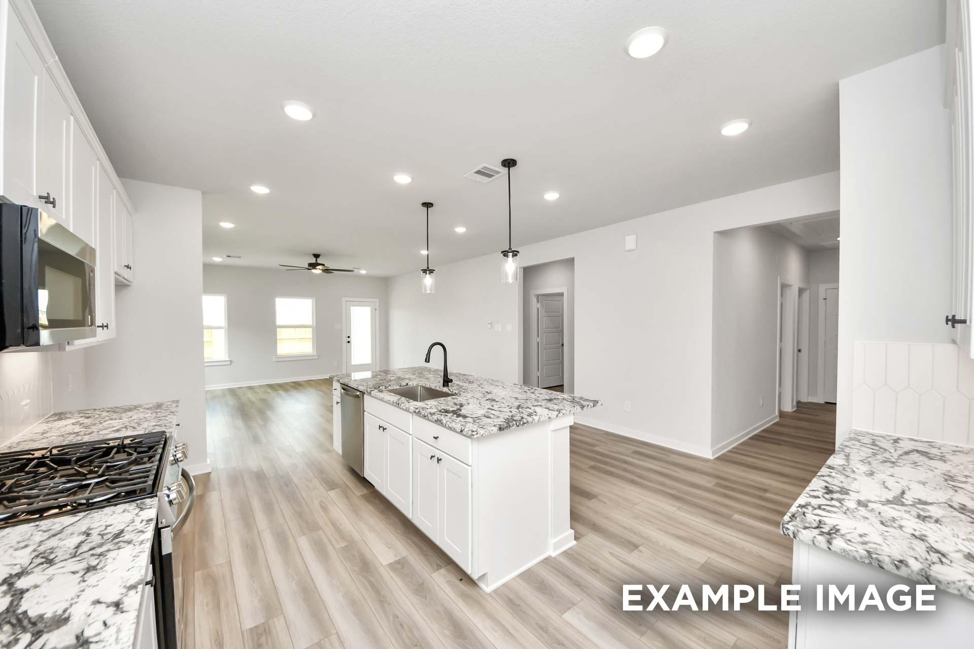 Open-concept kitchen in The Sorrento showcasing white cabinetry, granite countertops, and a large island in Crosby, Texas.