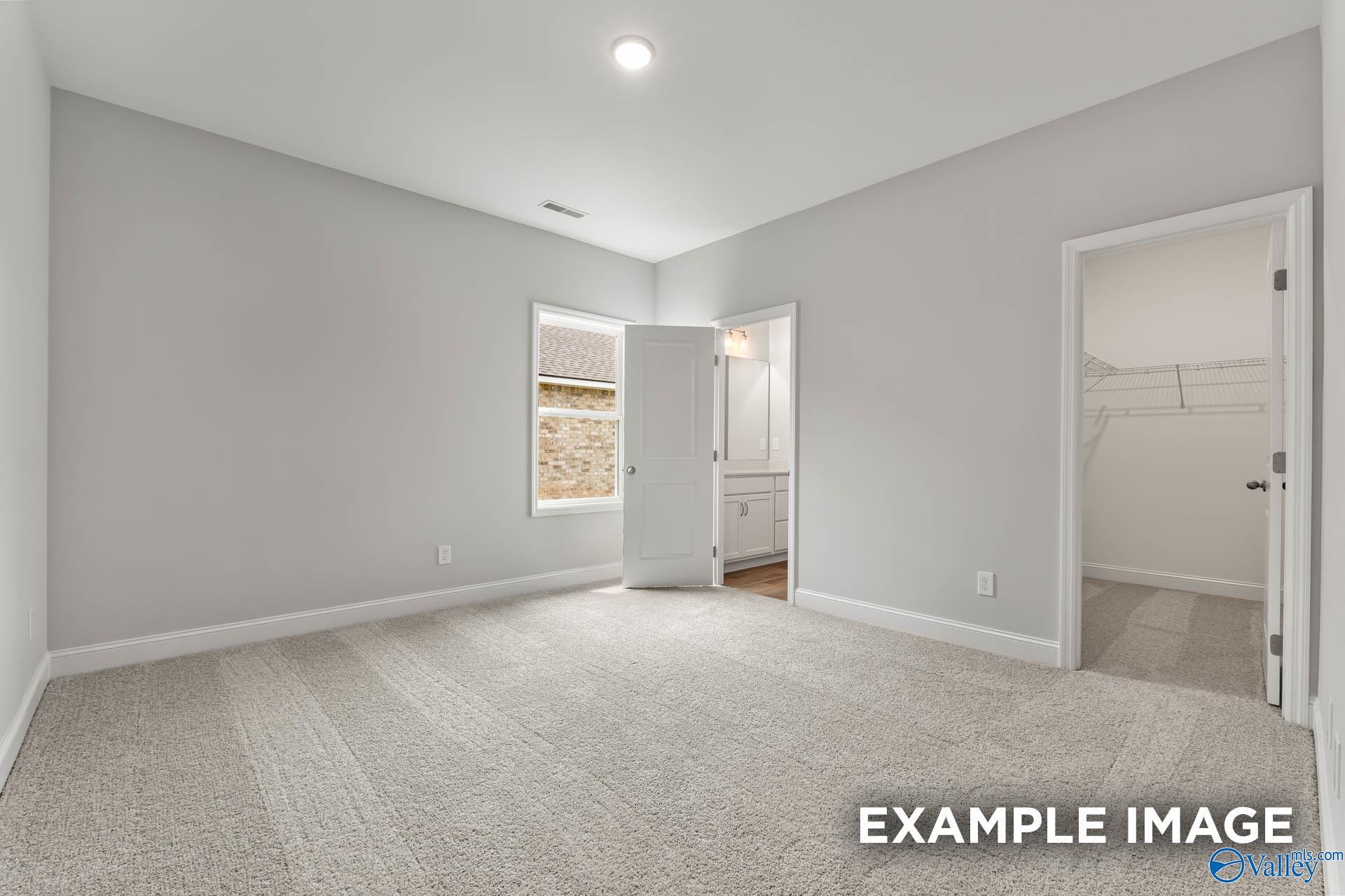Bright carpeted bedroom with walk-in closet and private bath access in Davidson Homes' The Butler plan at Blue Spring, Huntsville