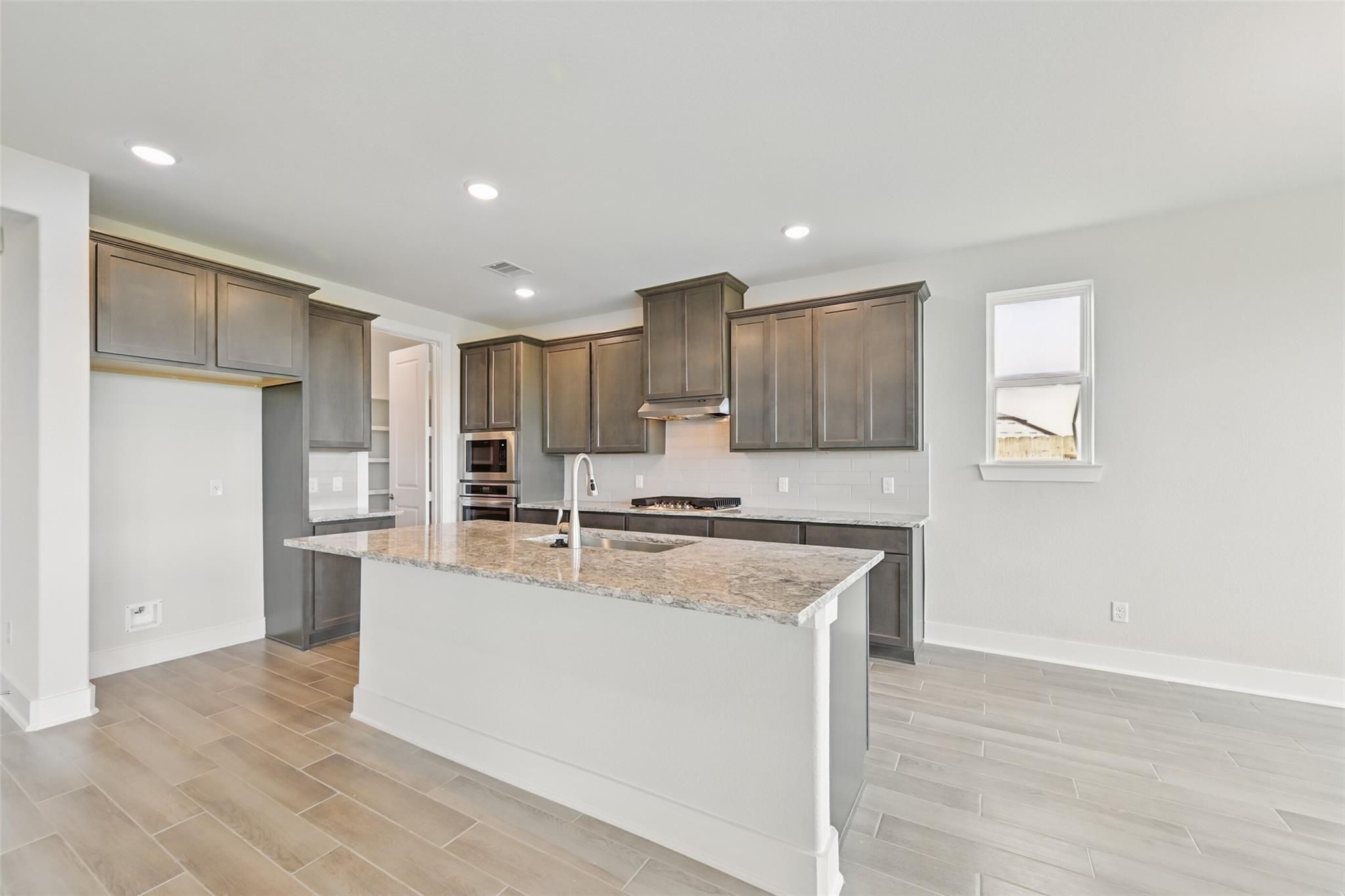 Modern kitchen with gray shaker cabinets, granite island sink, stainless appliances in Davidson Homes Philip A, Lago Mar, Texas City