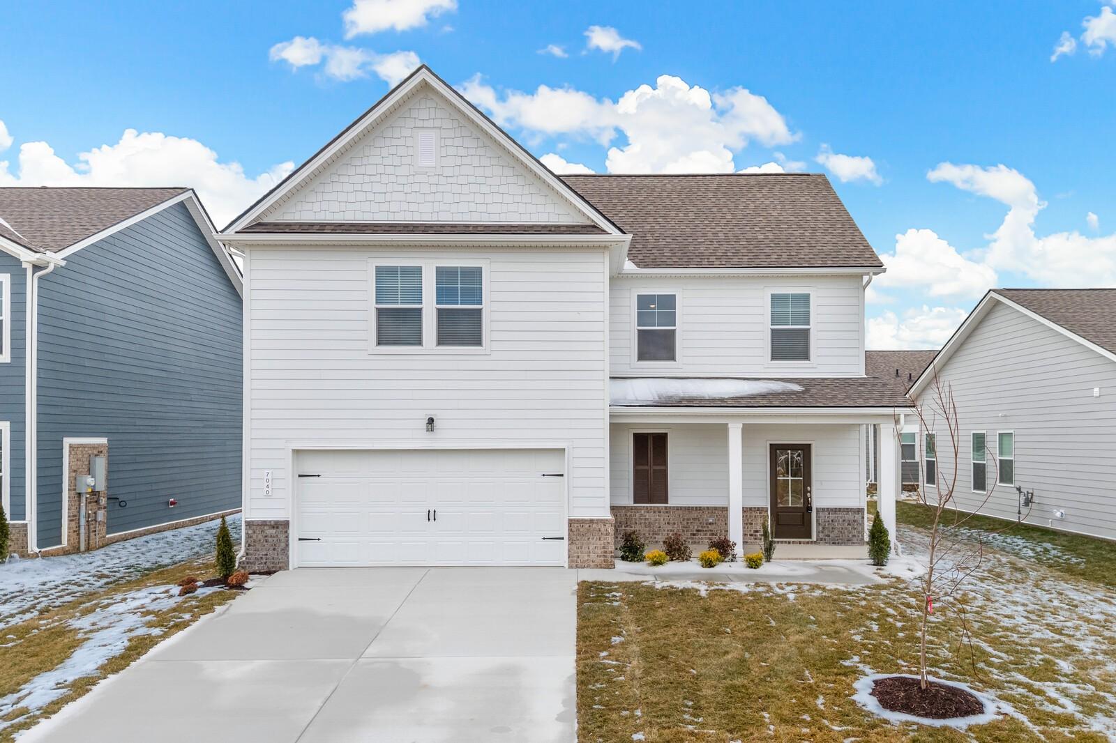 Two-story white home with 2-car garage, covered porch, and snowy front yard in Sage Farms, White House, Tennessee - Davidson Homes The Gordon C