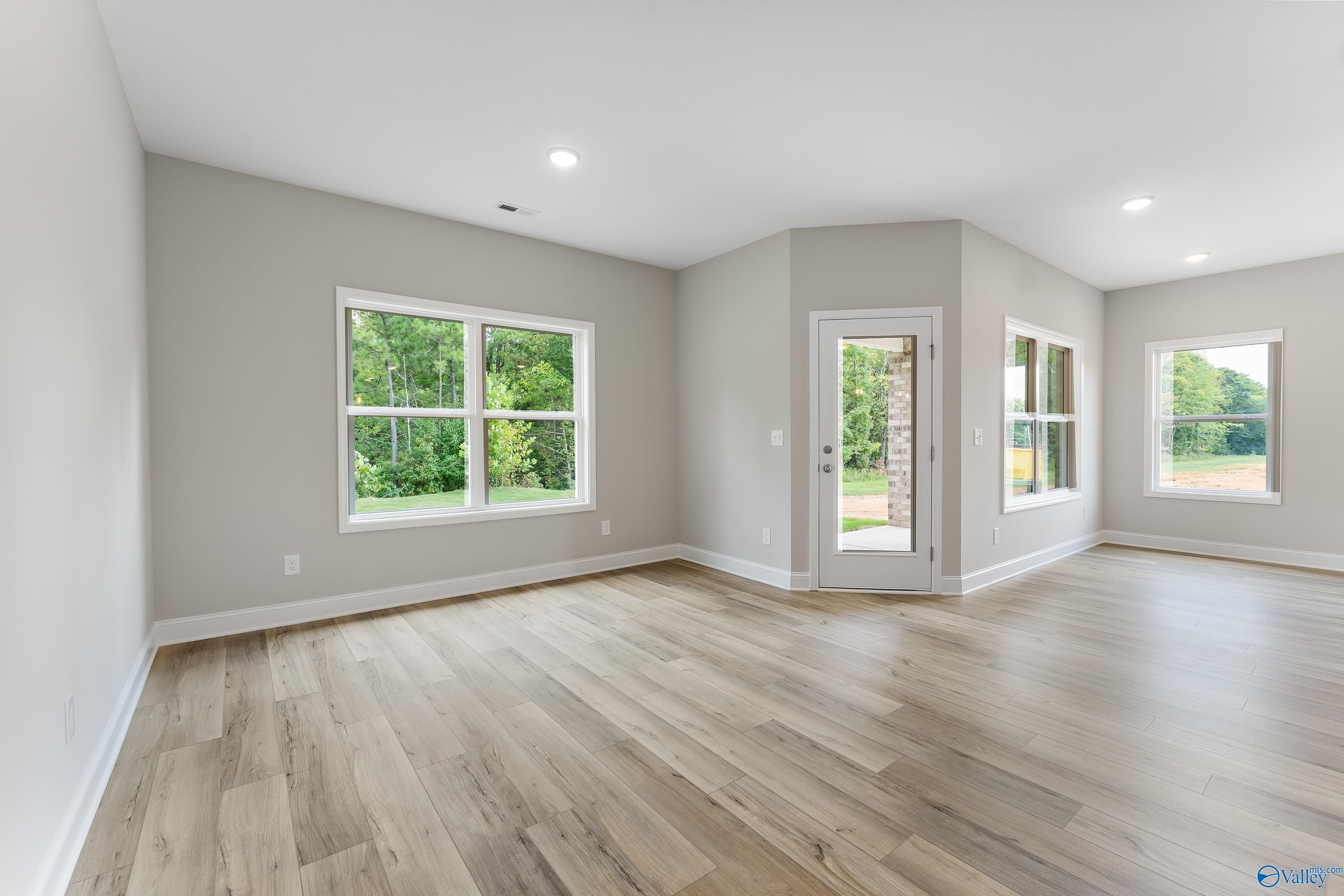 Spacious living room with hardwood floors, large windows, and glass patio door in Davidson Homes The Franklin, Huntsville, Alabama