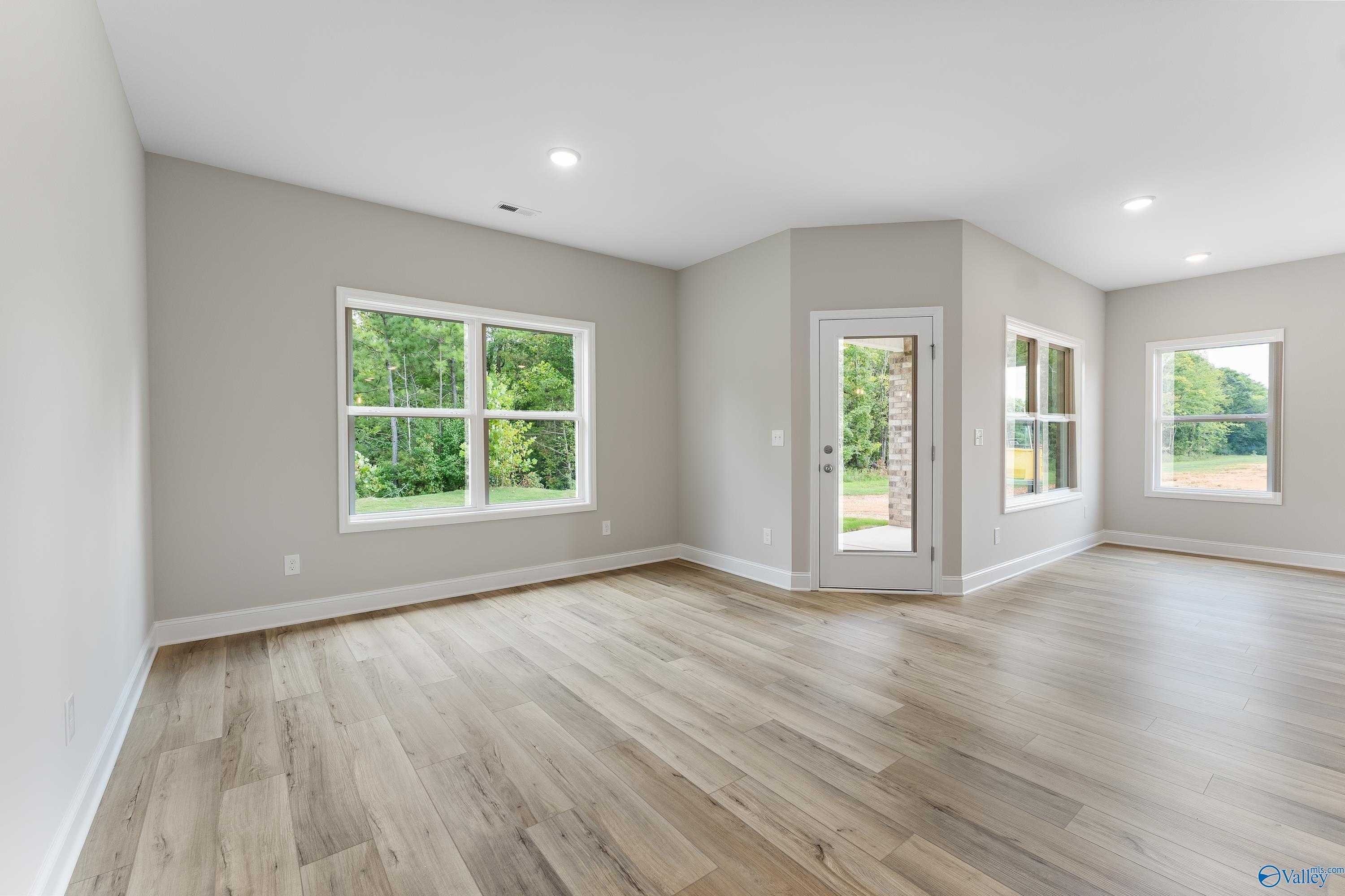 Spacious living room with hardwood floors, large windows, and glass patio door in Davidson Homes The Franklin, Huntsville, Alabama