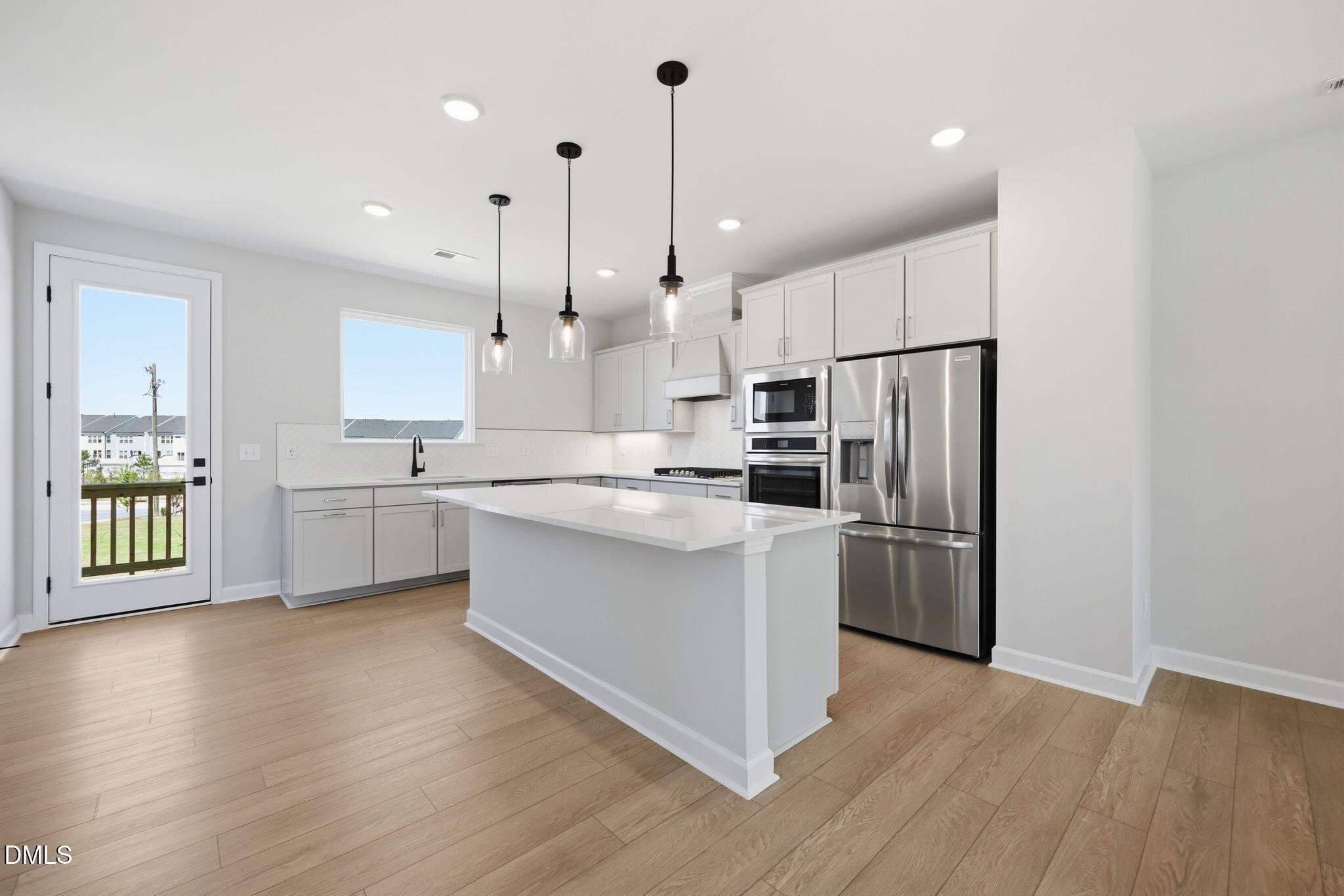 Modern kitchen with white island, stainless steel appliances, and pendant lighting in The Avery floor plan, Knightdale, NC.
