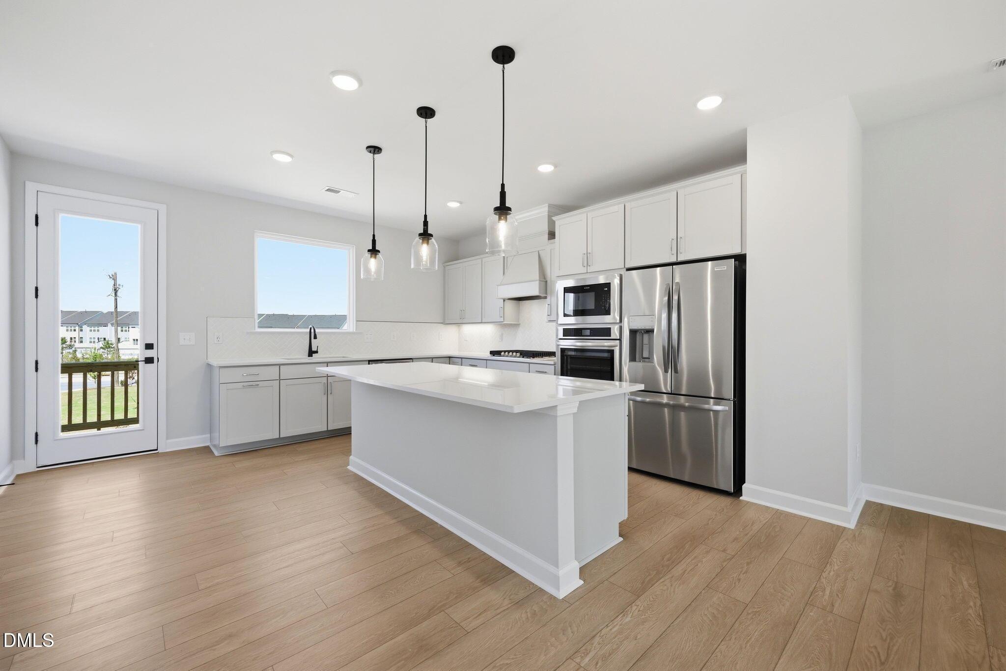 Modern kitchen with white island, stainless steel appliances, and pendant lighting in The Avery floor plan, Knightdale, NC.