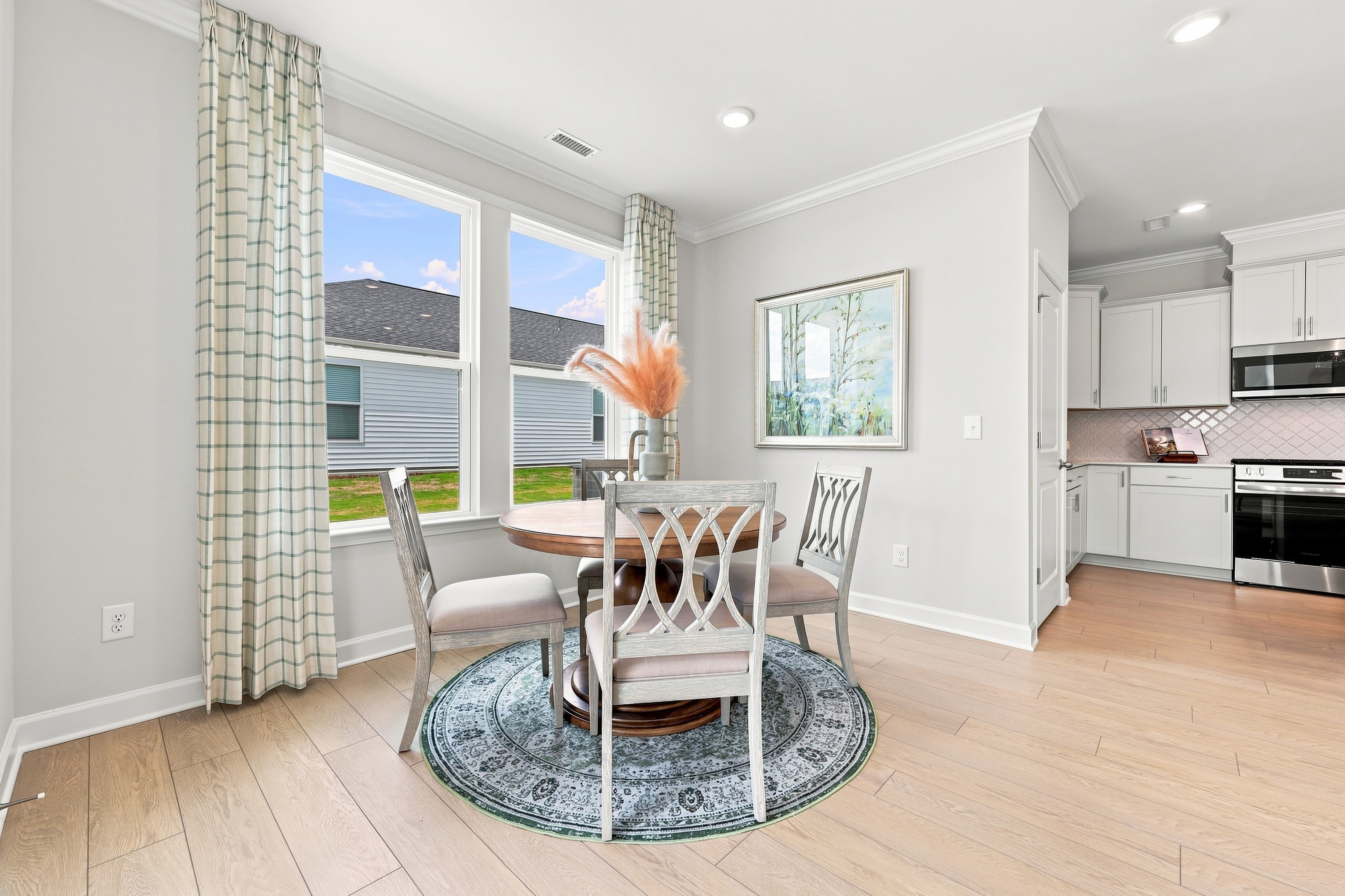 Bright dining nook in The Daphne D by Davidson Homes featuring a round table and open-concept view of the modern kitchen.