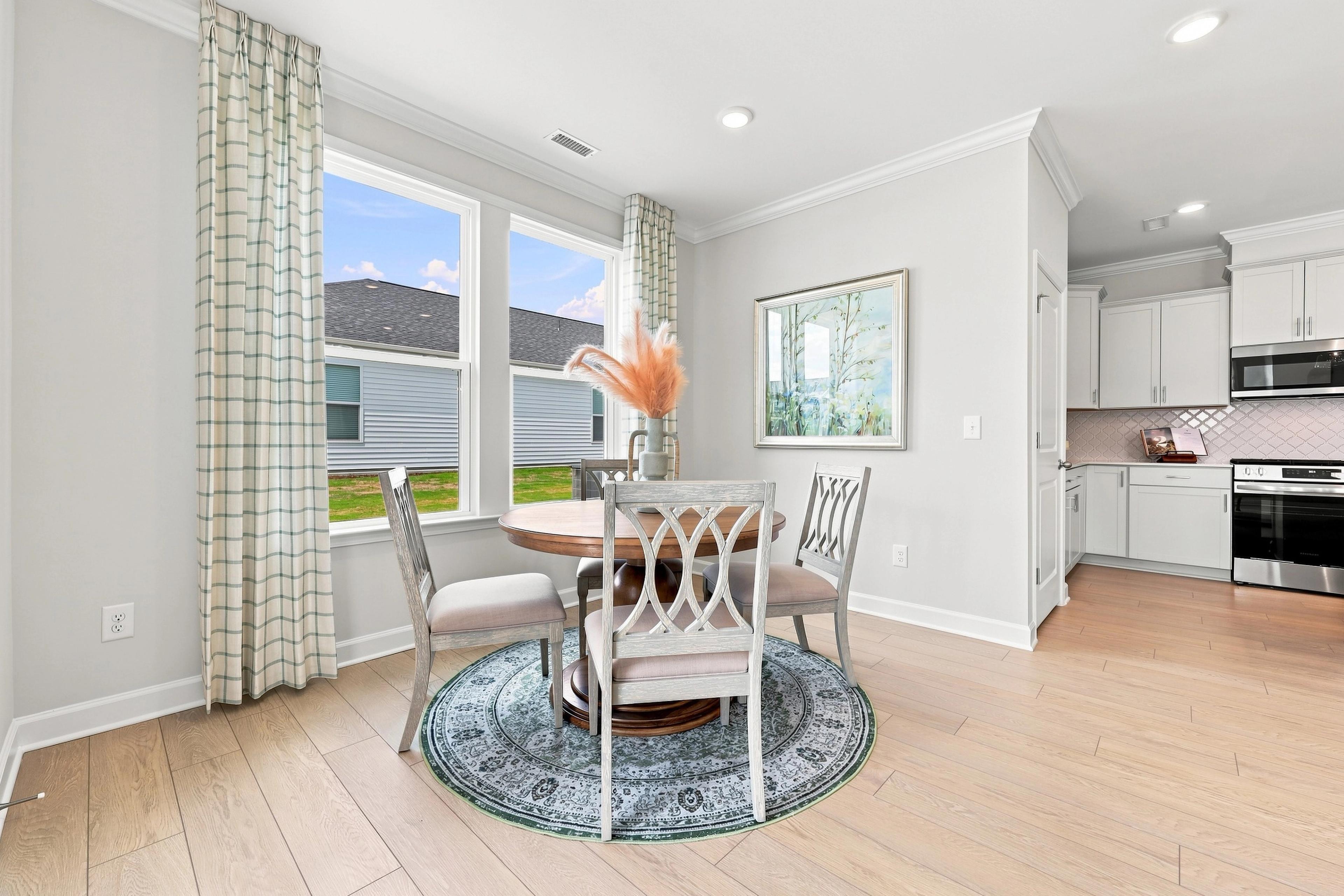 Bright dining nook in The Daphne D by Davidson Homes featuring a round table and open-concept view of the modern kitchen.