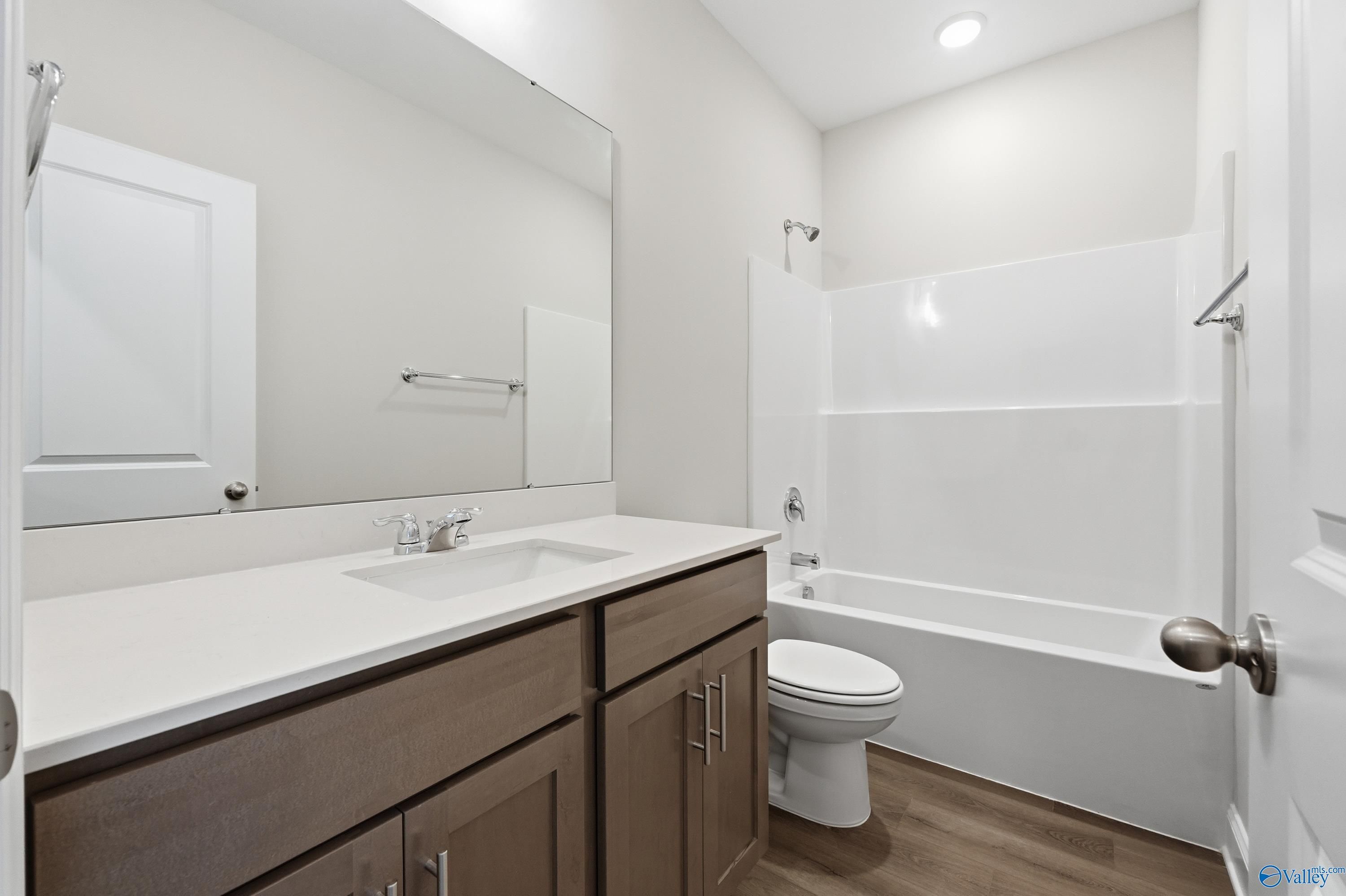 Modern secondary bathroom with white subway tile shower-tub combo, double quartz vanity, and wood cabinetry in Davidson Homes The Daphne C, Arab, AL
