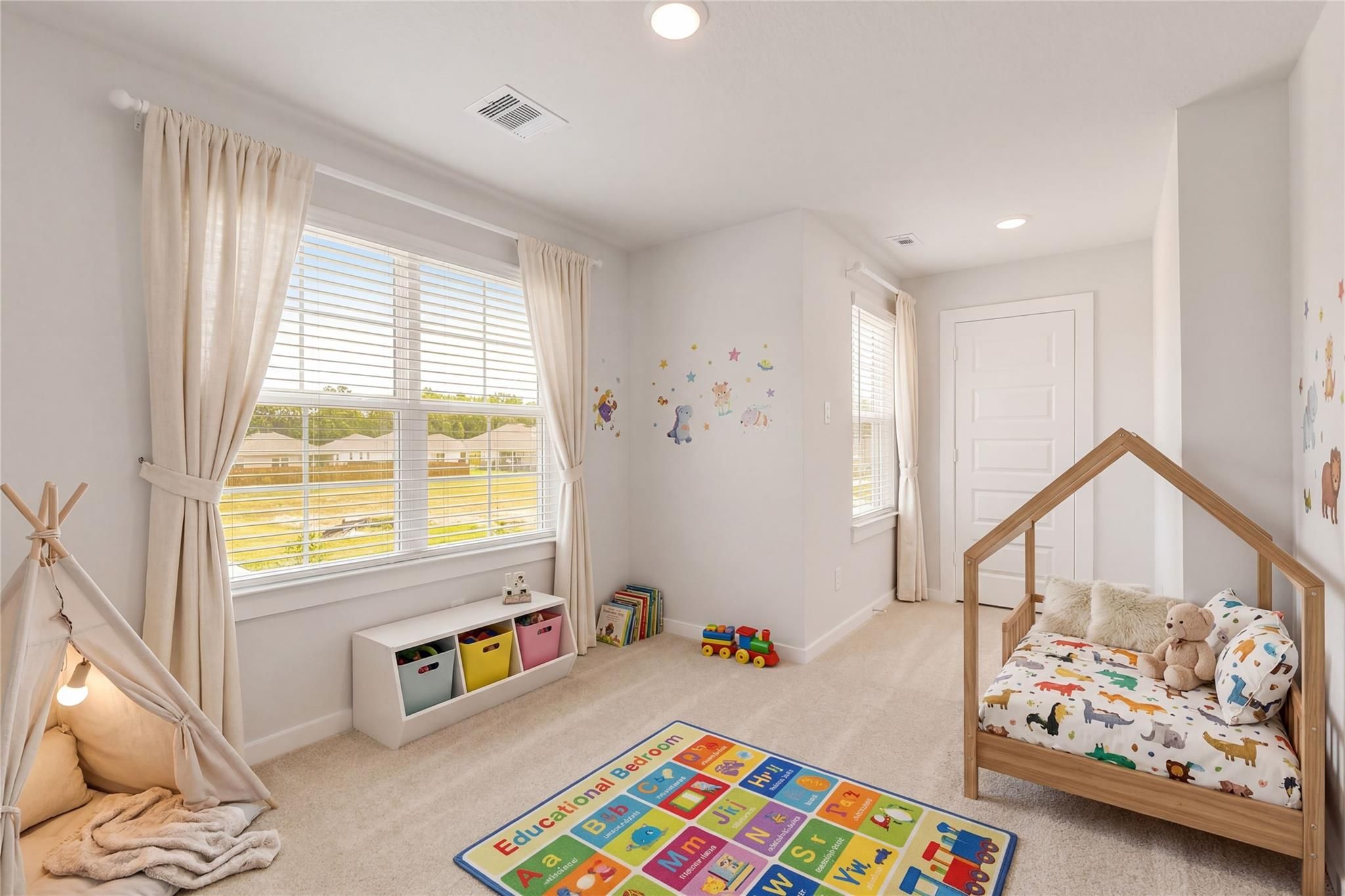 Cozy kids' playroom with ABC rug, toy tipi tent, and animal-print daybed in Davidson Homes The Brazos E, Cleveland, Texas