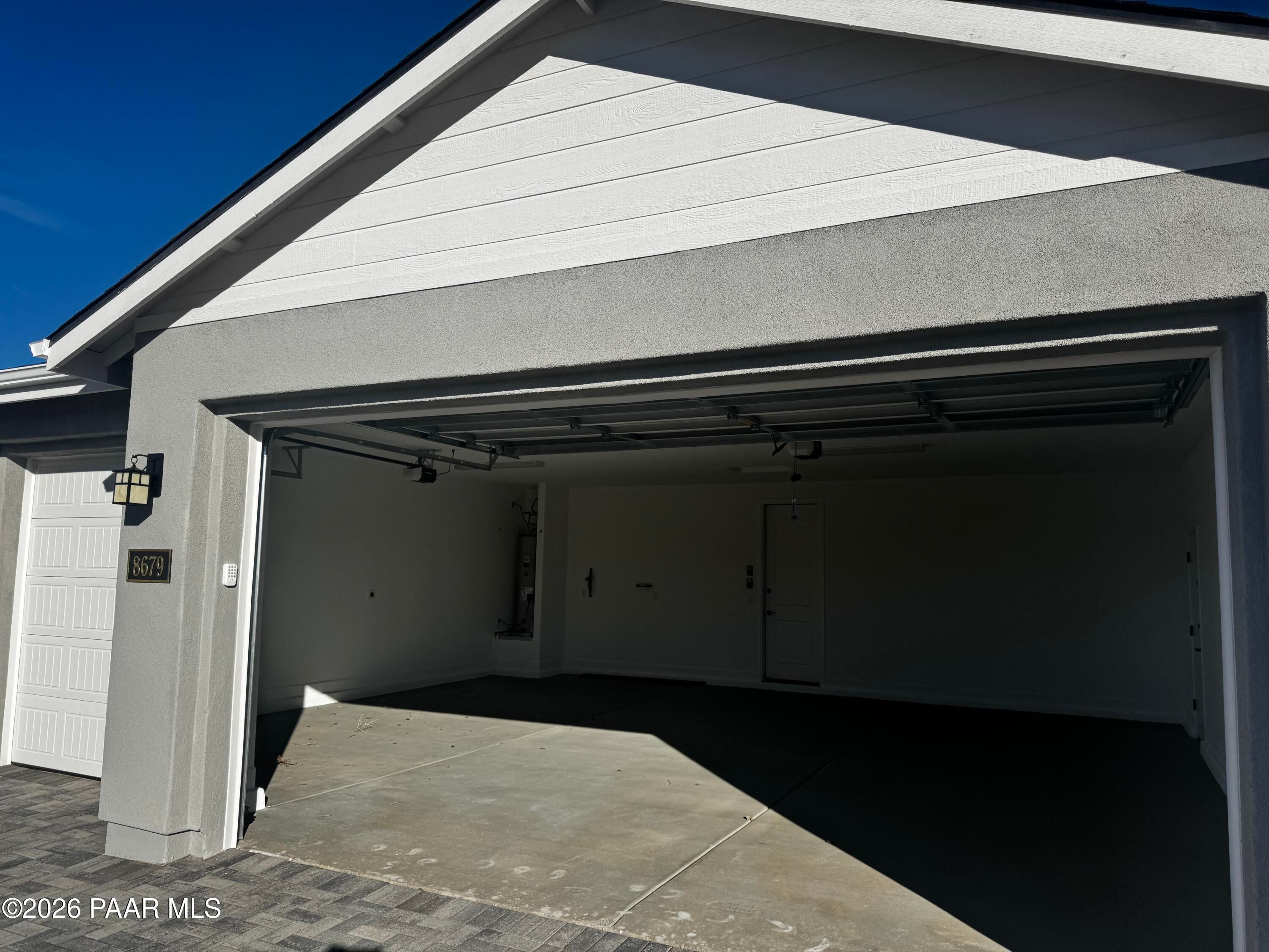 Spacious 3-car garage with open doors in modern stucco home, The Monarch B by Evermore Homes in Morningstar, Prescott Valley, Arizona