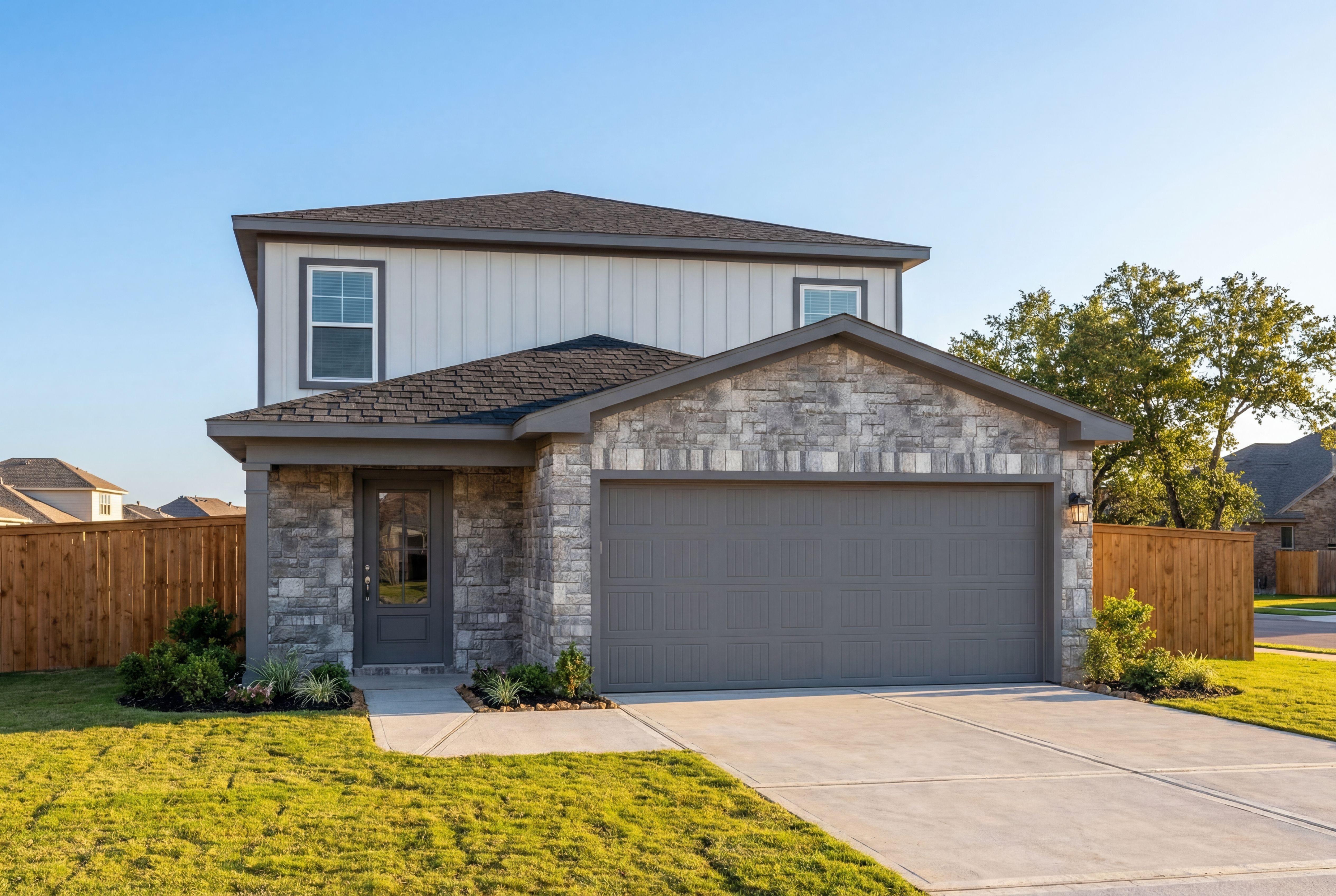 Modern two-story San Marcos home elevation with stone accents, gray siding, two-car garage, and landscaped front yard in Magnolia Texas