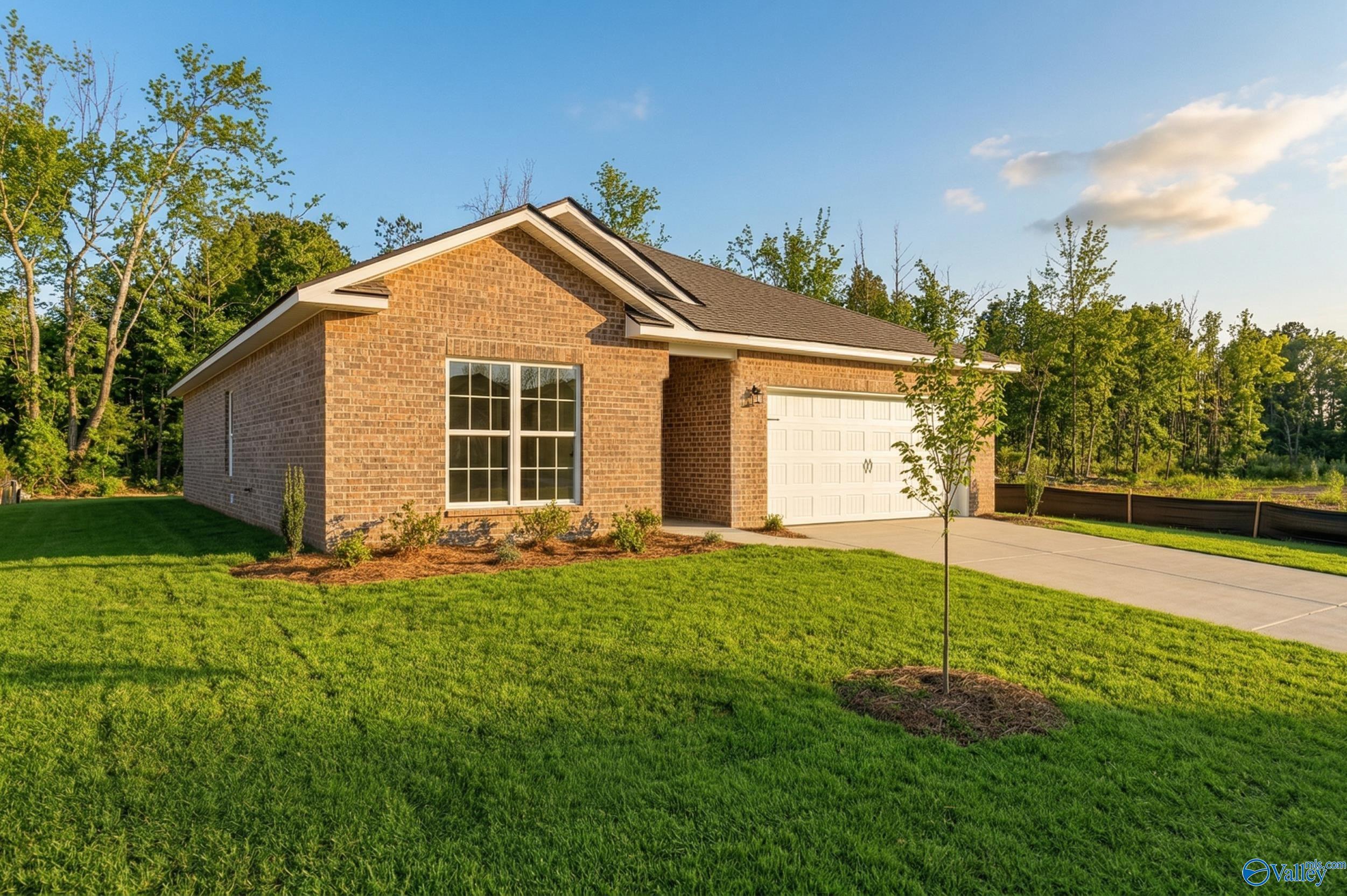 Brick 1-story home with 2-car garage, large windows, and landscaped yard in Spragins Cove, Huntsville, Alabama by Davidson Homes