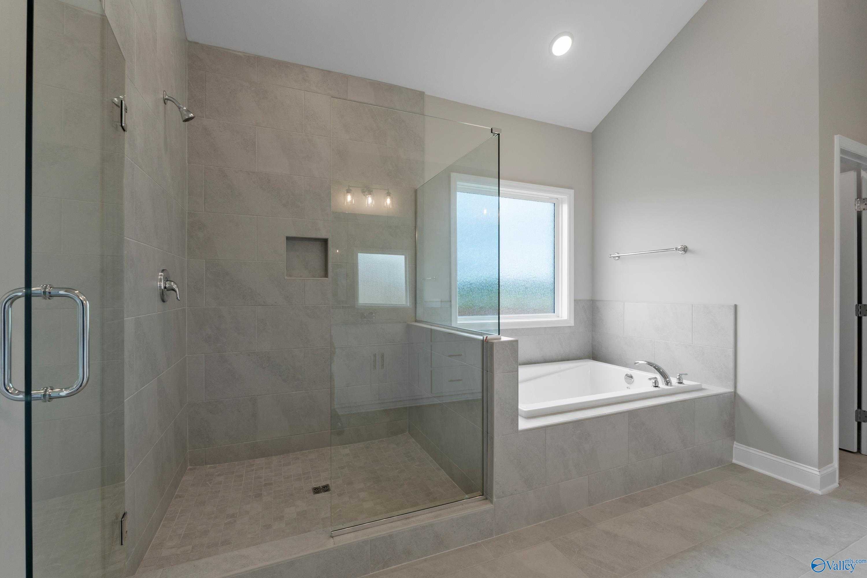 Luxurious master bathroom with glass shower enclosure and freestanding tub in Davidson Homes The Finleigh, Meridianville, Alabama