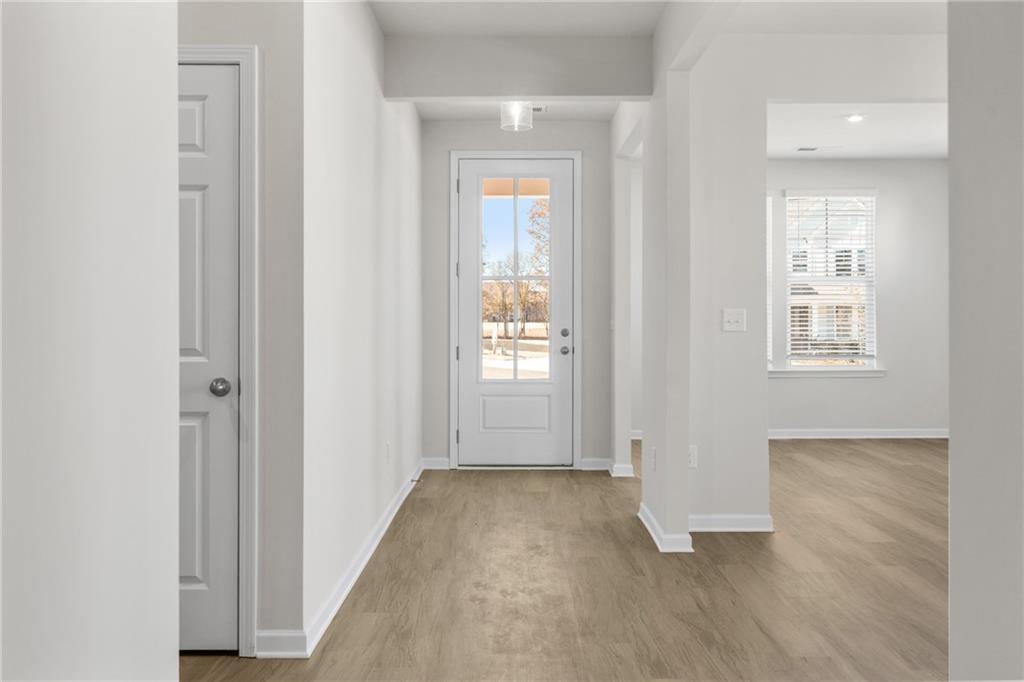 Bright entryway with white door and wood-style flooring in The Glenwood A floor plan at Wehunt Meadows, Hoschton, Georgia.