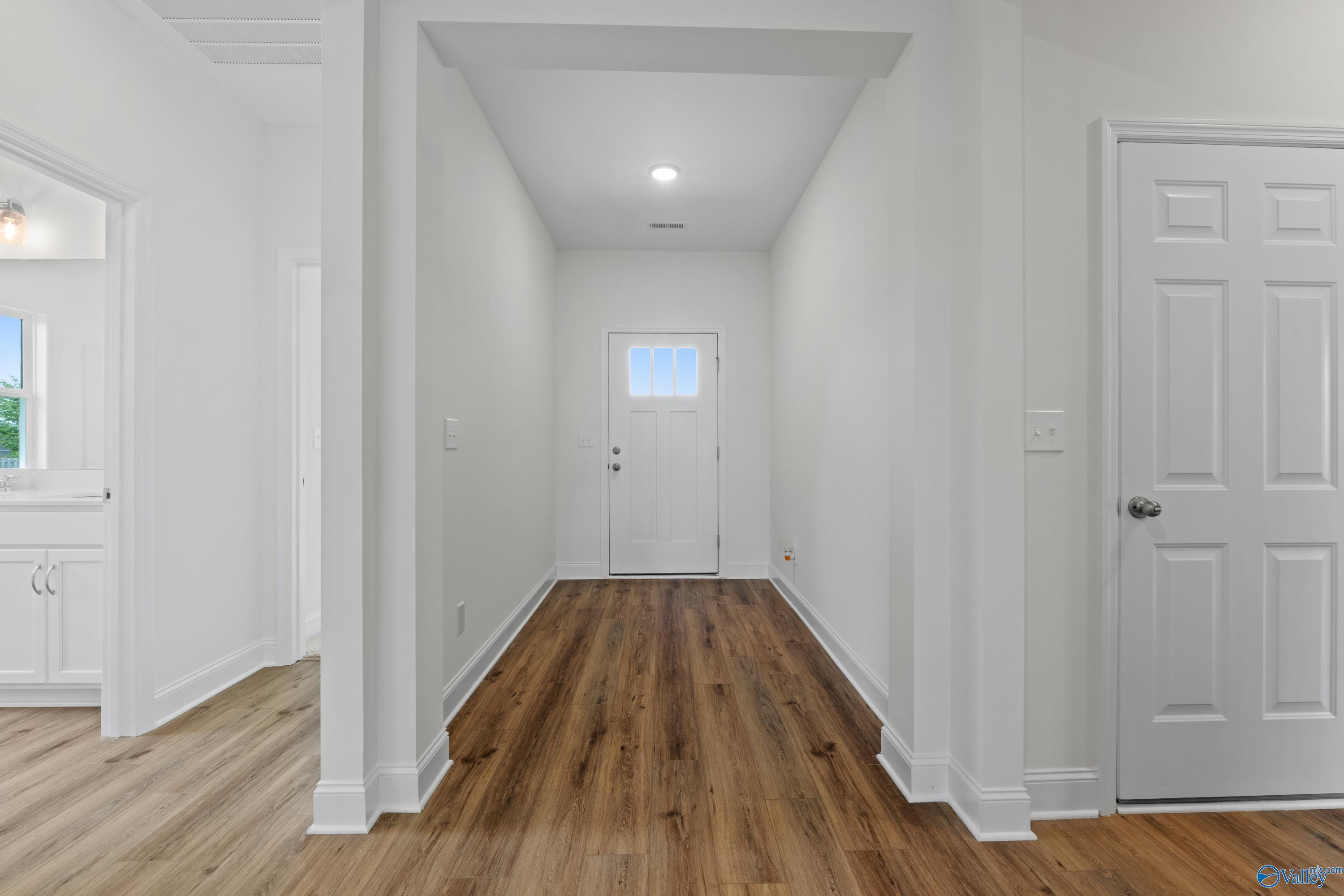 Bright entryway with wood-look flooring and white trim in The Everett B floor plan by Davidson Homes in Athens, Alabama.