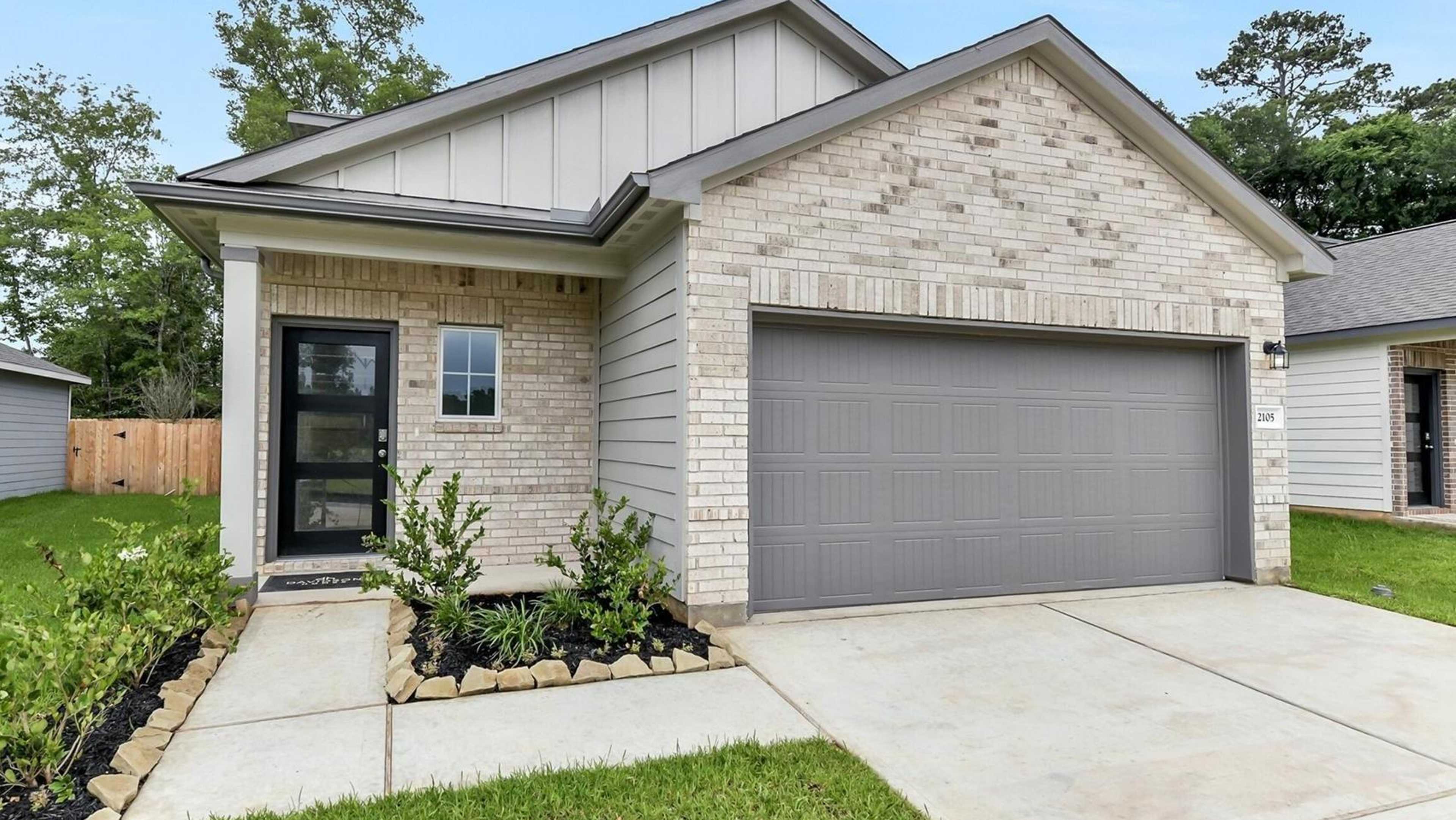 Modern Davidson Homes brick residence at 2105 Caney Creek Lane open house, with gray garage, porch, and lush front yard landscaping