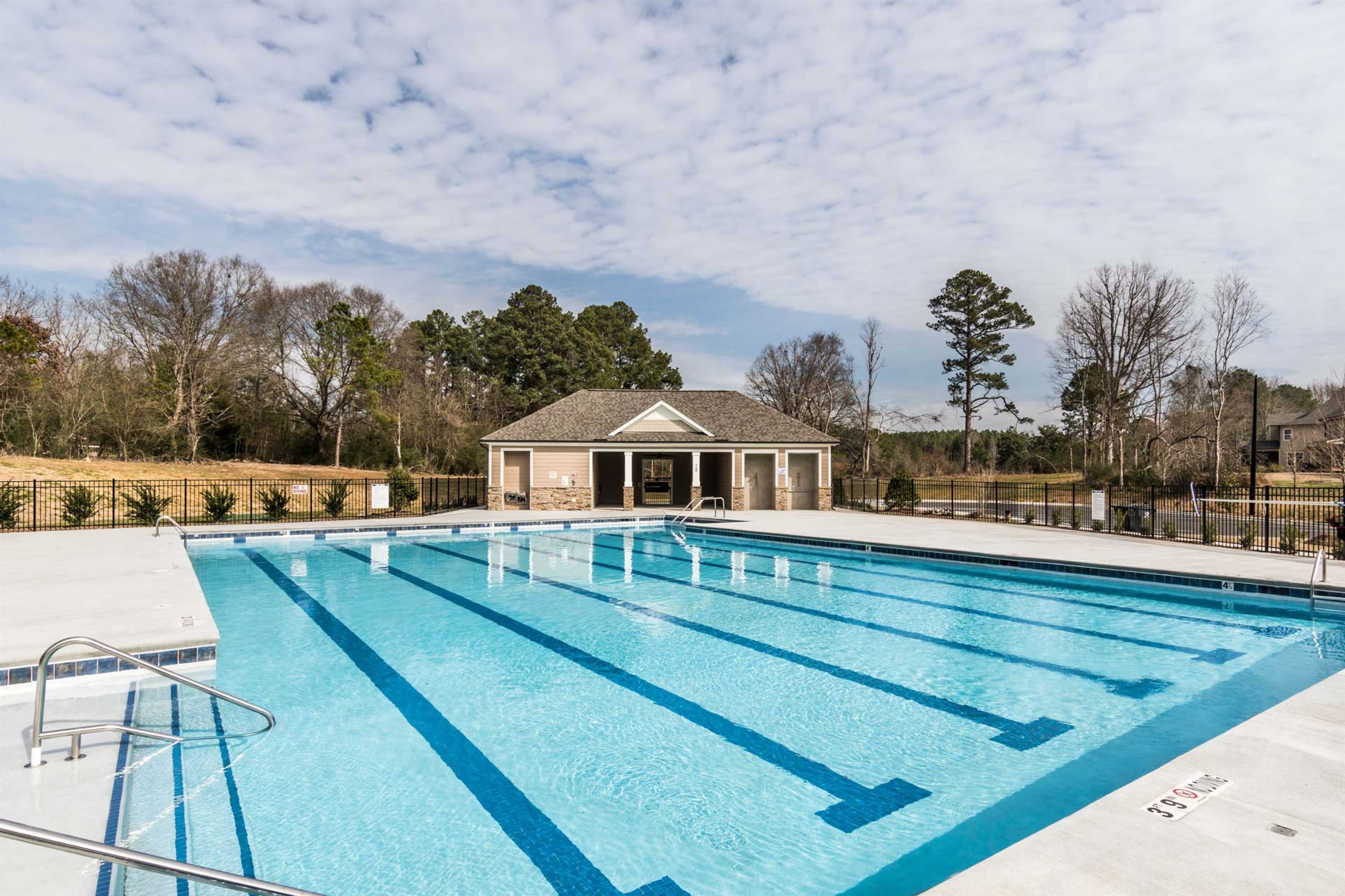Resort-style lap swimming pool at Glenmere in Knightdale NC with blue lanes, deck, and brick pavilion amid trees