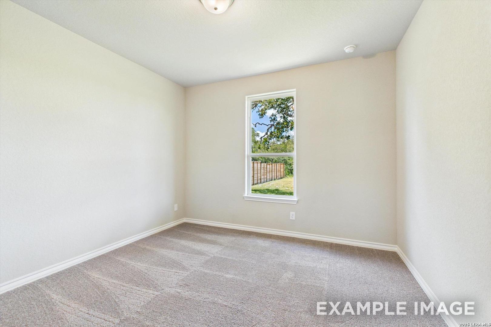 Bright, neutral-toned bedroom with carpeted flooring in The Foster F floor plan at Potranco Oaks in Castroville, Texas.